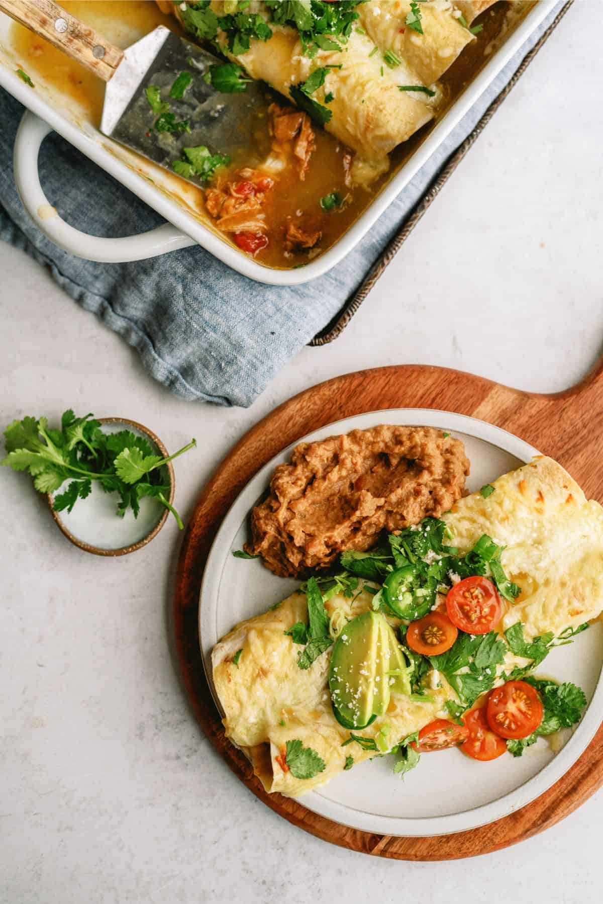 2 Slow Cooker Chile Verde Pork Enchiladas on a plate with a side of beans