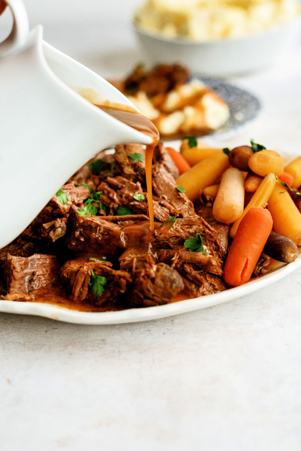 Pouring gravy over shredded Slow Cooker Copycat Texas Roadhouse Beef Pot Roast