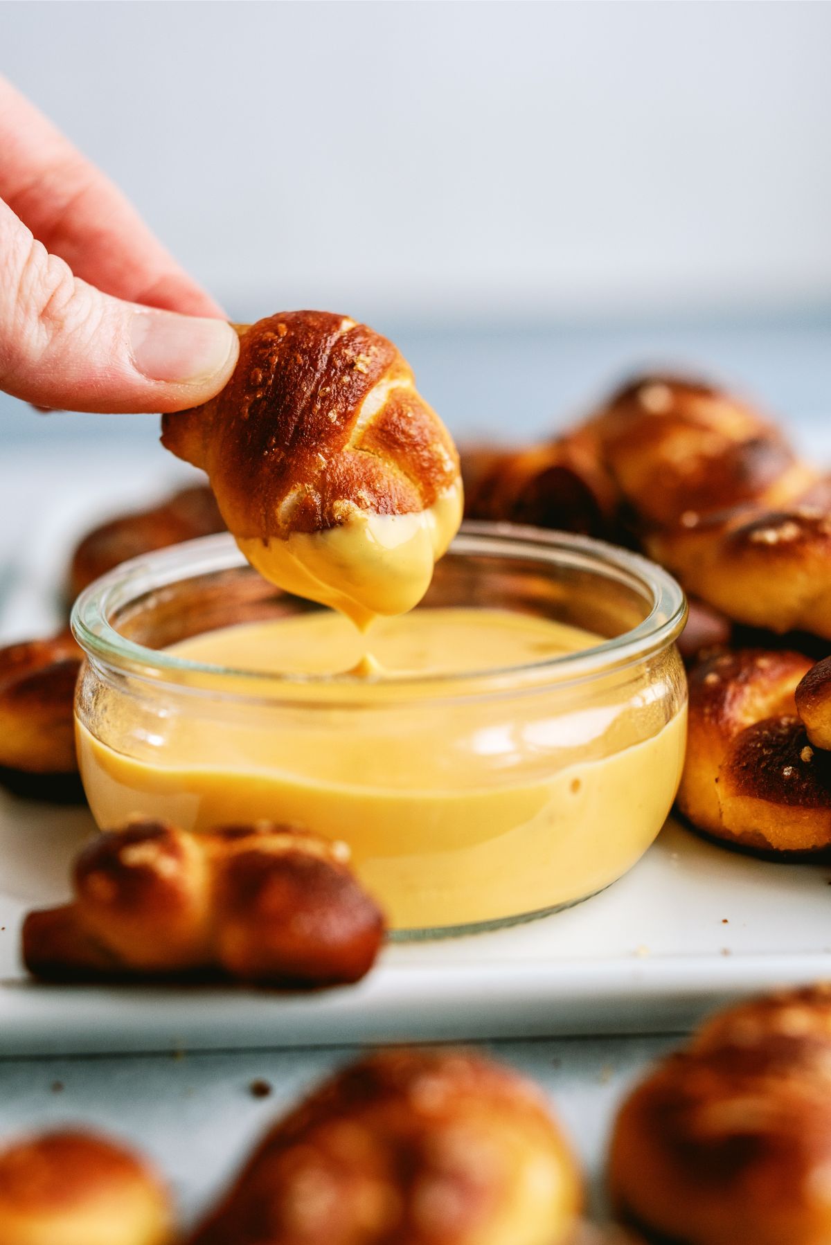 Twisted Soft Pretzel Bites surrounding queso with one bite being dipped