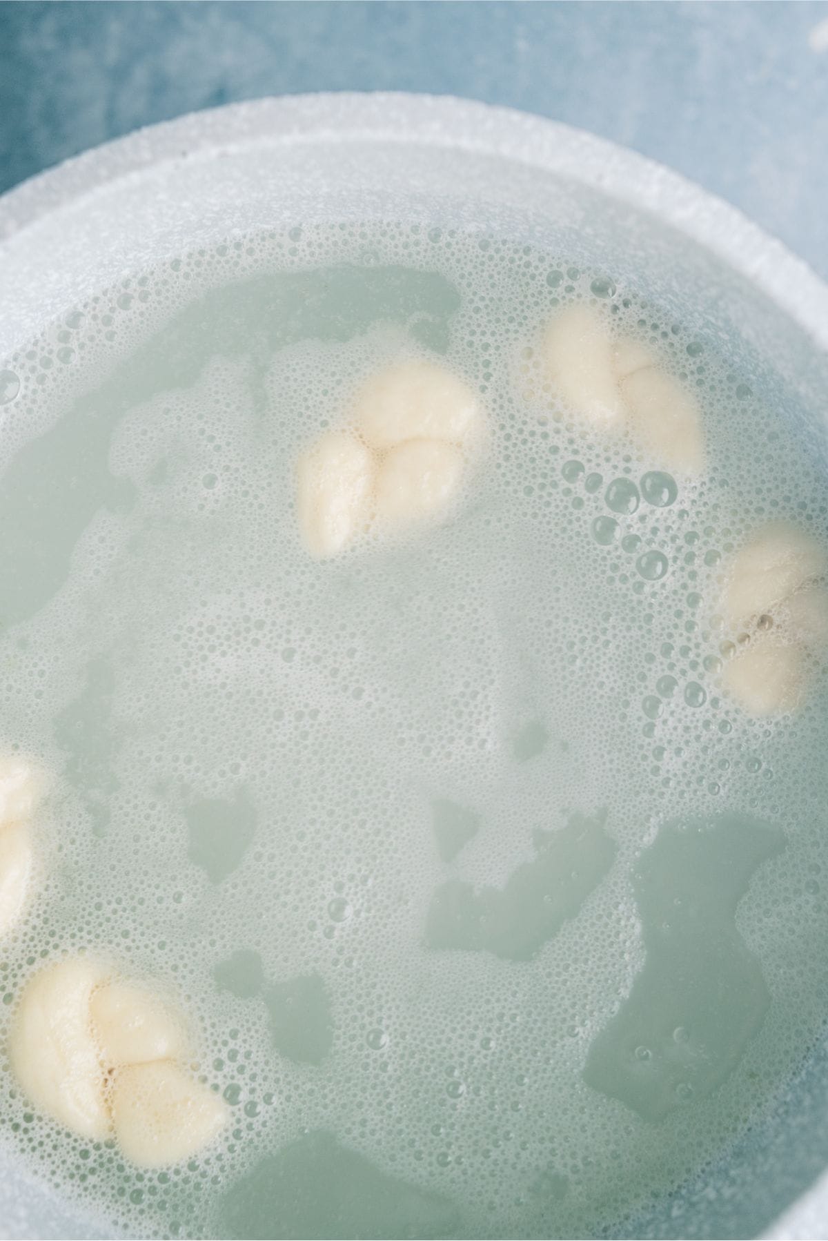 6 dough knots dropped into a pot of boiling water