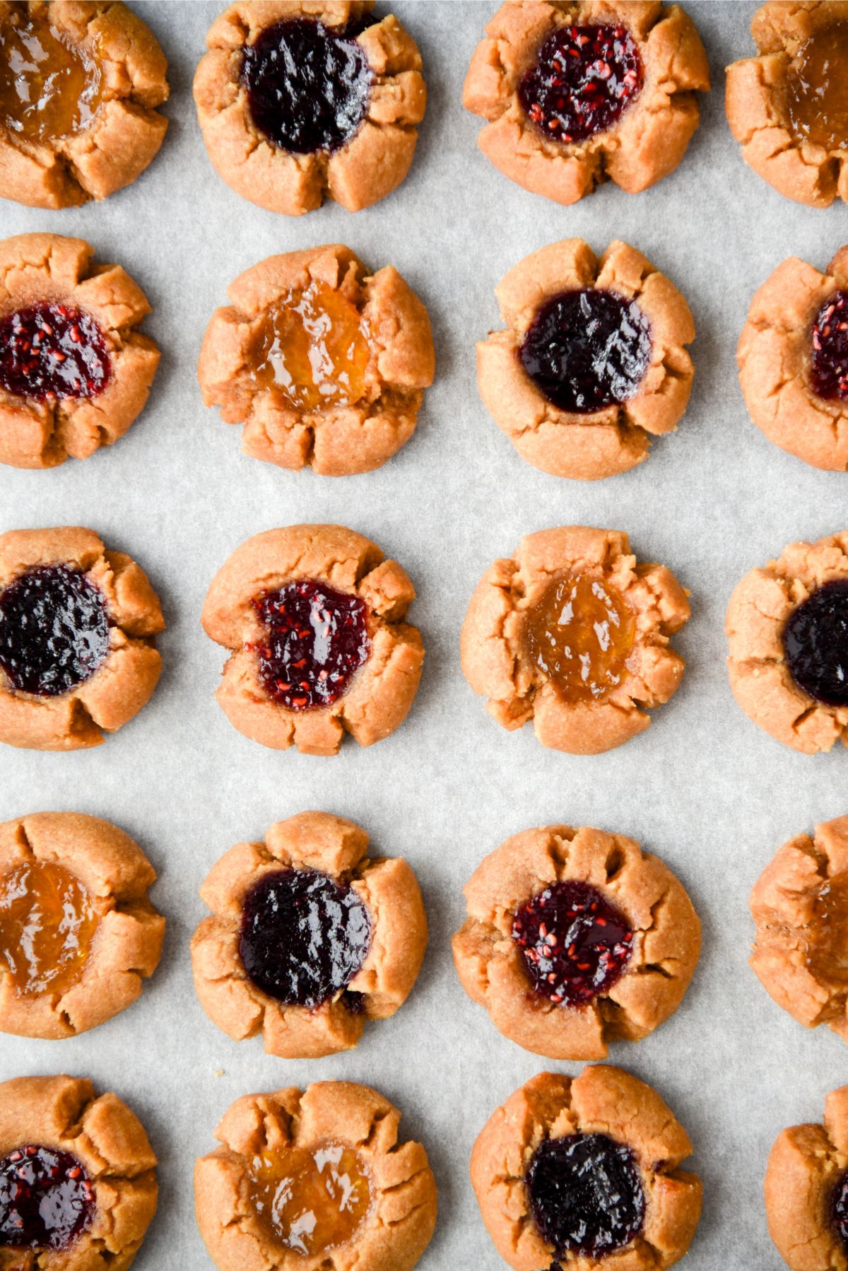5 Ingredient Peanut Butter and Jam Thumbprint Cookies lined up on parchment paper