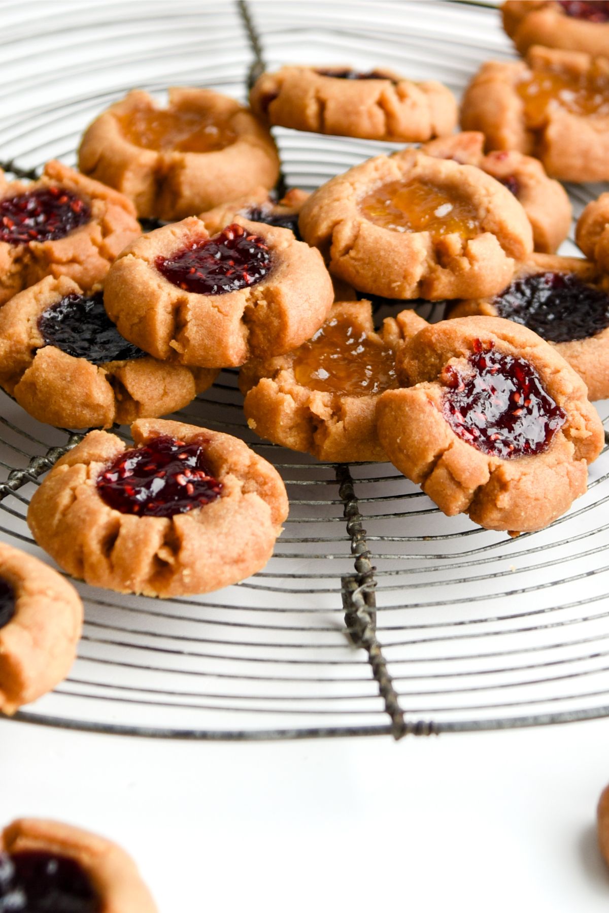 5 Ingredient Peanut Butter and Jam Thumbprint Cookies on a cake stand