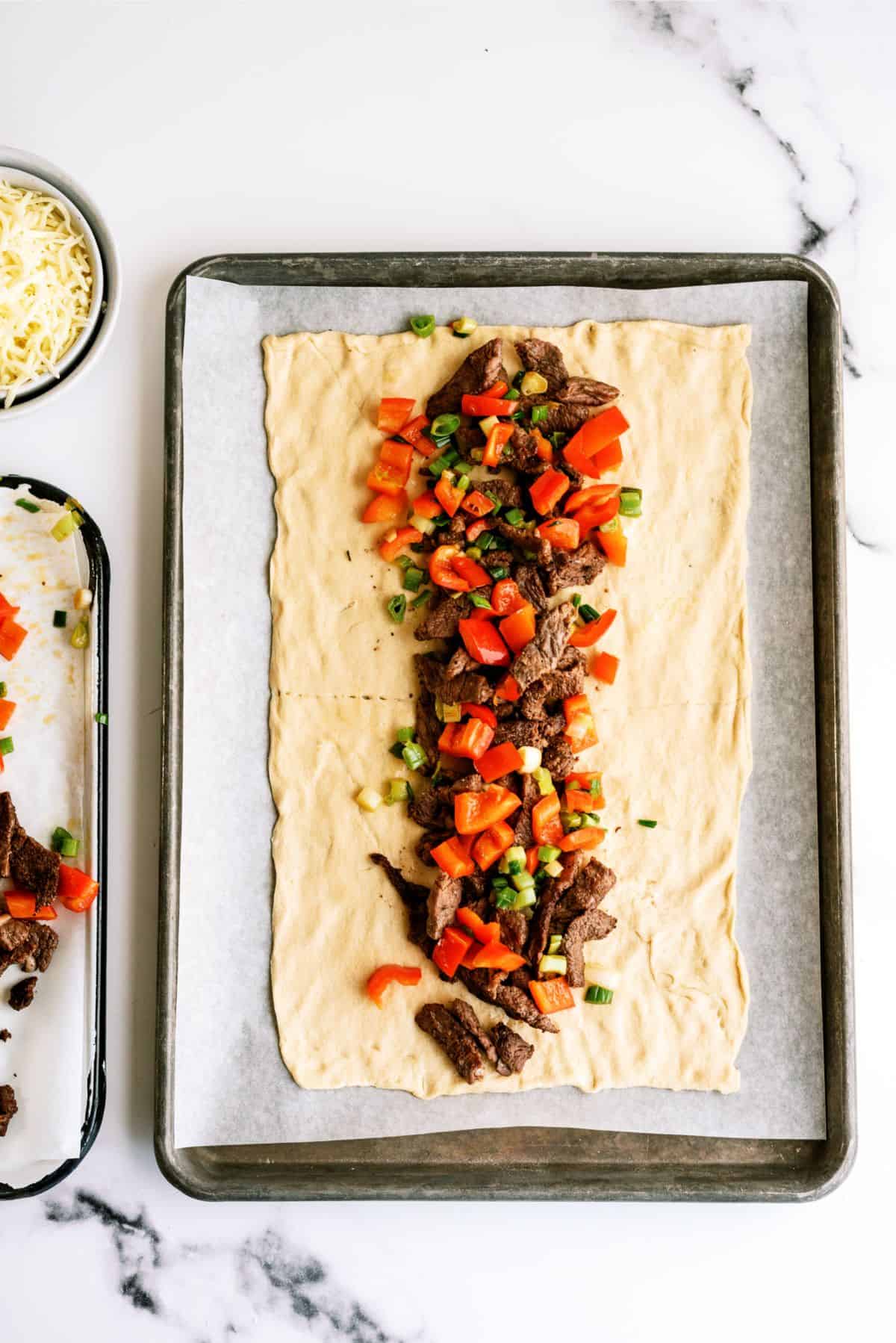 Crescent roll, rolled out into a rectangle with steak and pepper filling inside