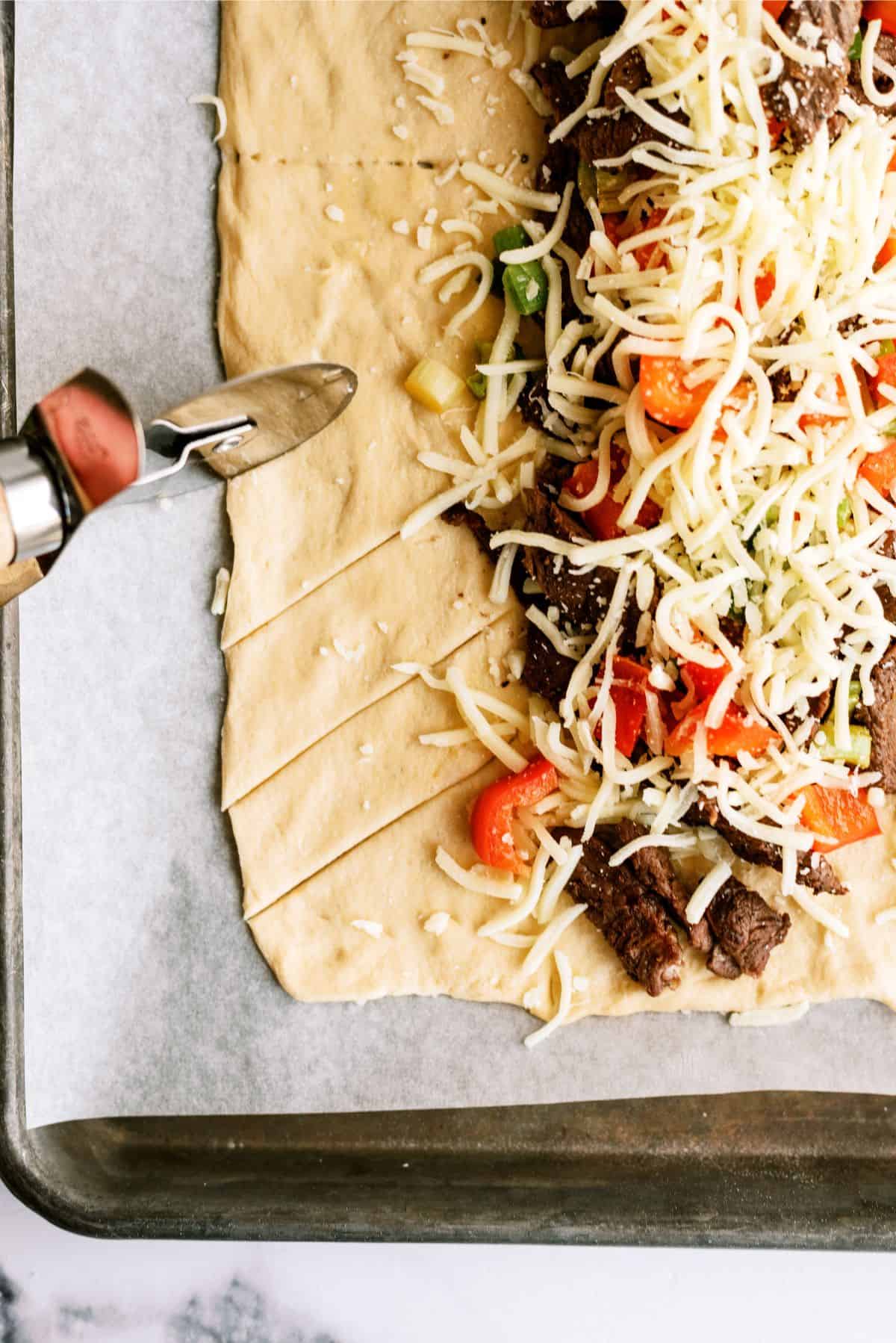 Pizza cutter cutting slits in the crescent dough