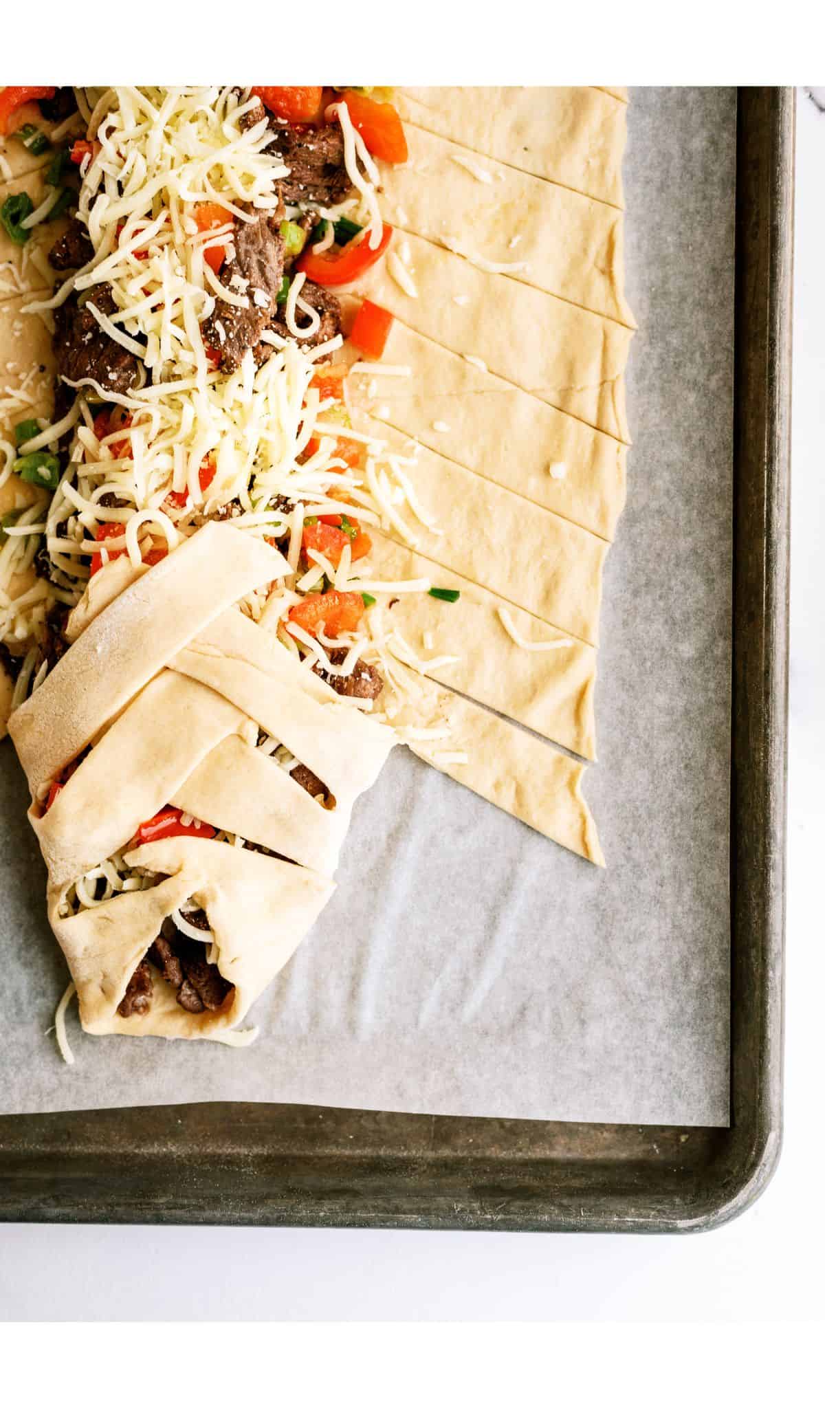 Braiding the dough over the steak mixture in the middle