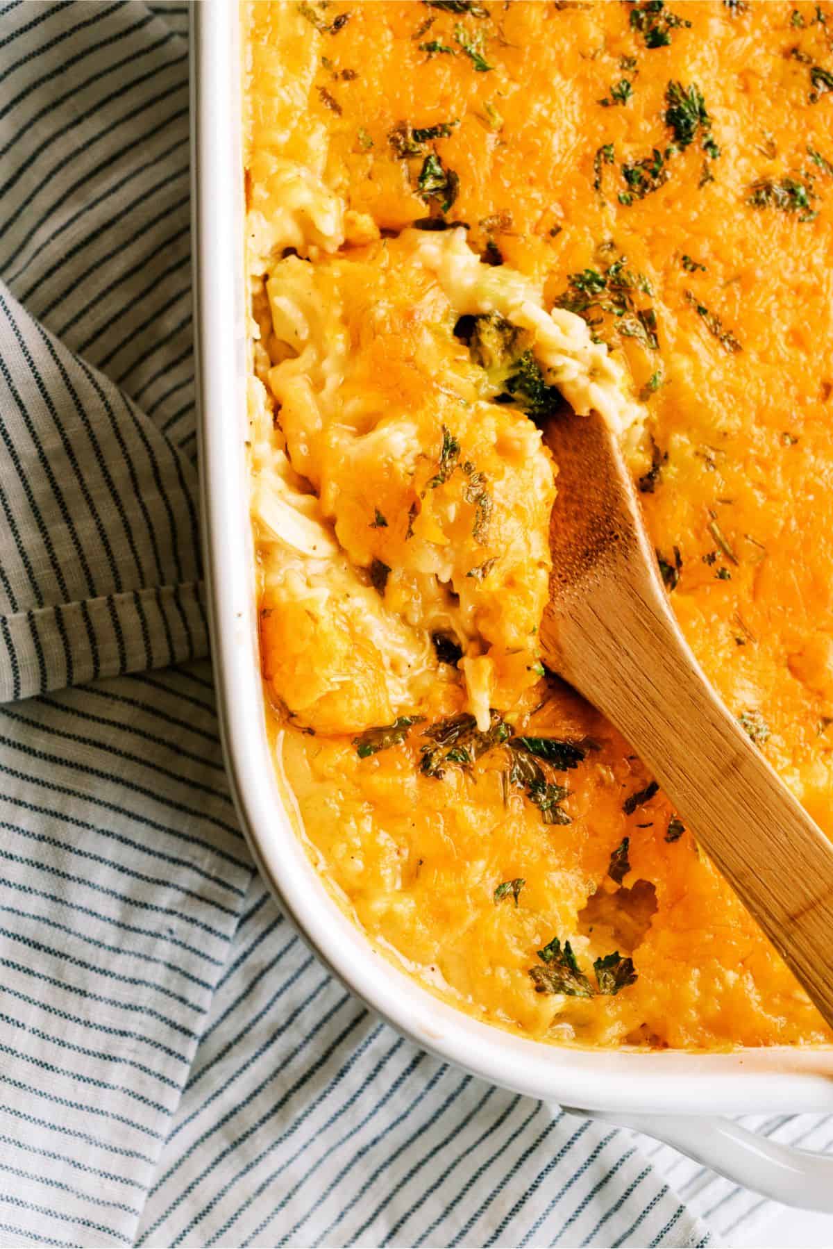 Cheesy Chicken Broccoli Rice Casserole Recipe (No Soup) in casserole dish with a wooden spoon