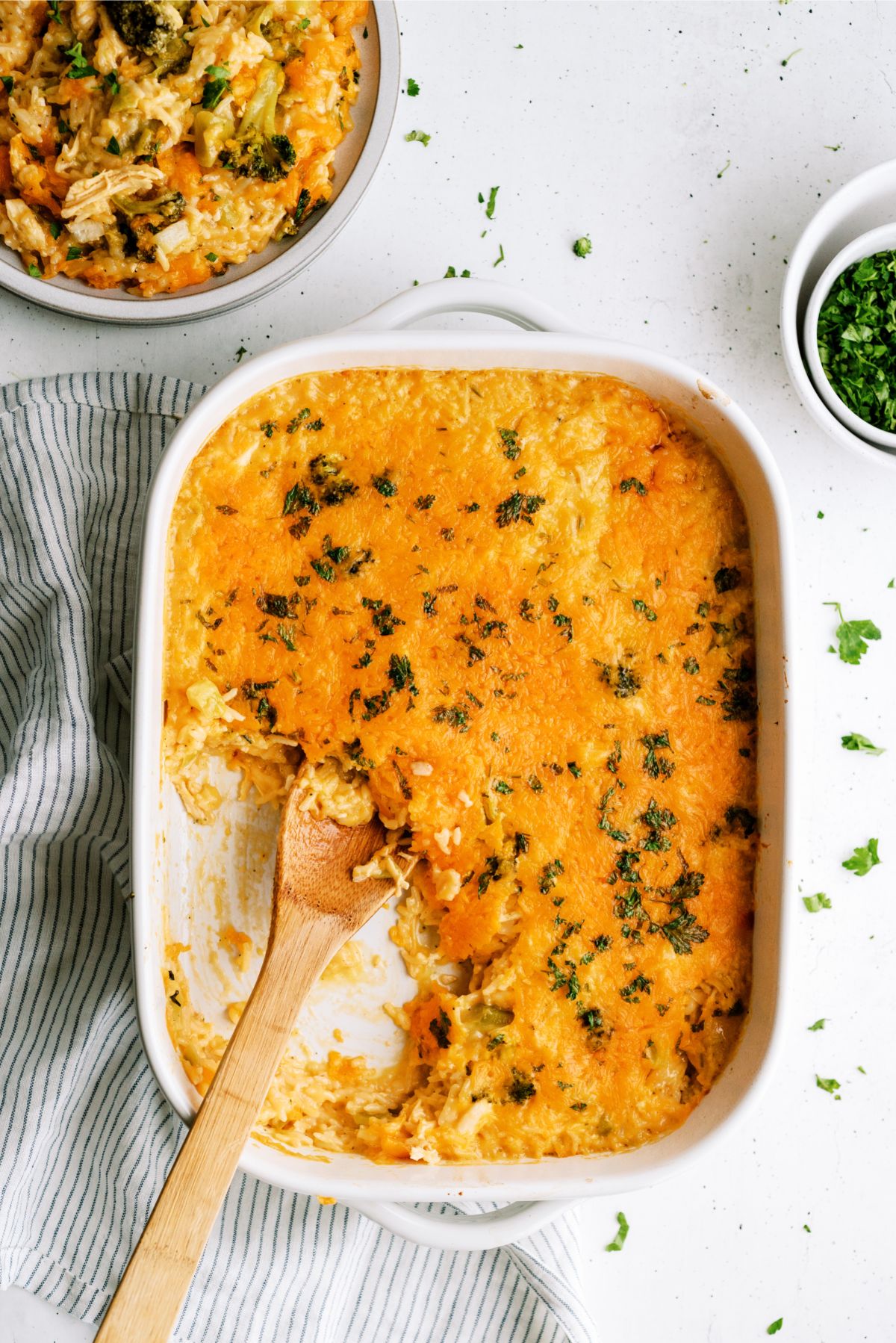 Cheesy Chicken Broccoli Rice Casserole Recipe (No Soup) in casserole dish with a wooden spoon spooning out a serving