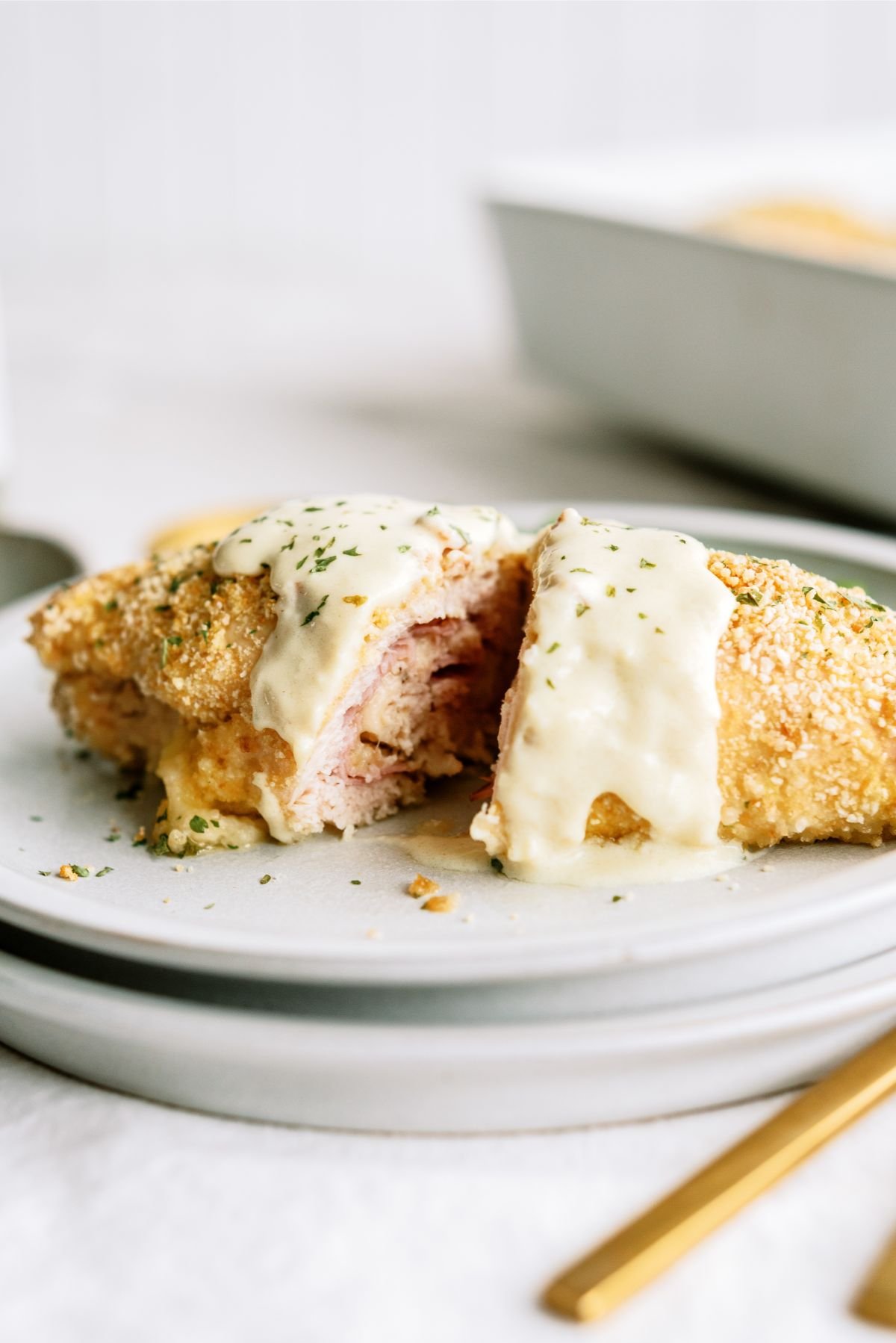 1 Easy Chicken Cordon Bleu on a serving plate, topped with sauce and cut in half