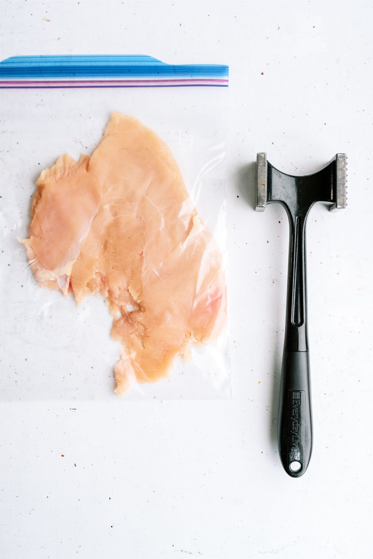 Chicken breast flattened in a plastic bag with a meat tenderizer