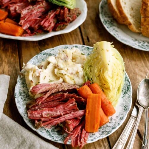 Instant Pot Corned Beef and Cabbage with potatoes on a dinner plate with a fork and knife.