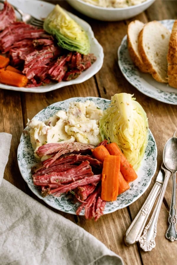 Instant Pot Corned Beef and Cabbage with potatoes on a dinner plate with a fork and knife.