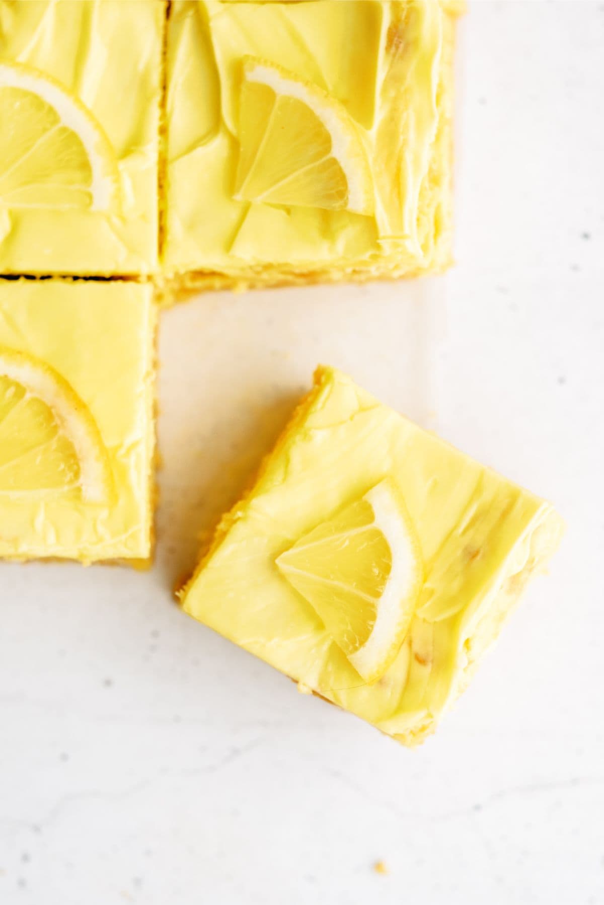 Lemon Cookie Cheesecake Bars cut into squares with a lemon slice on top