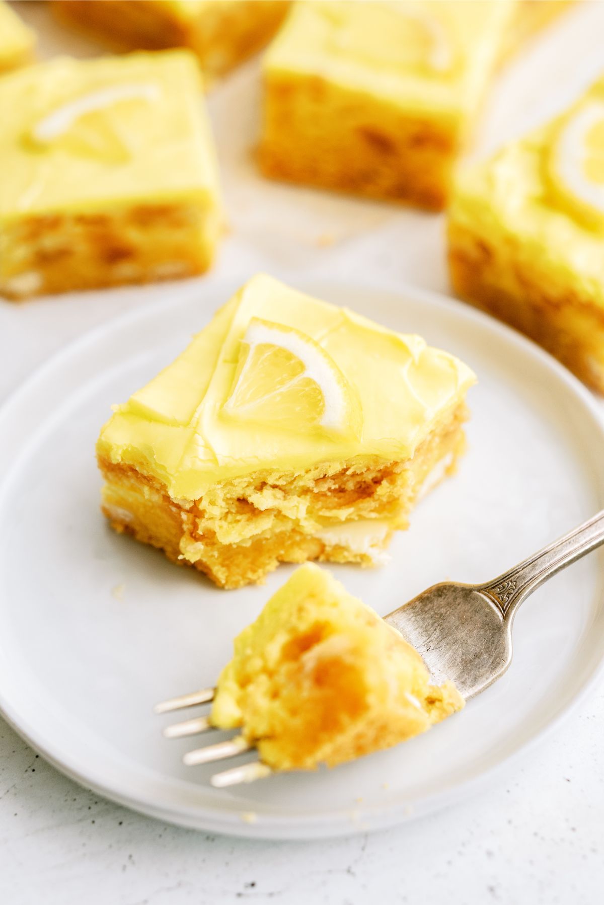 A fork taking a bite out of a Lemon Cookie Cheesecake Bars