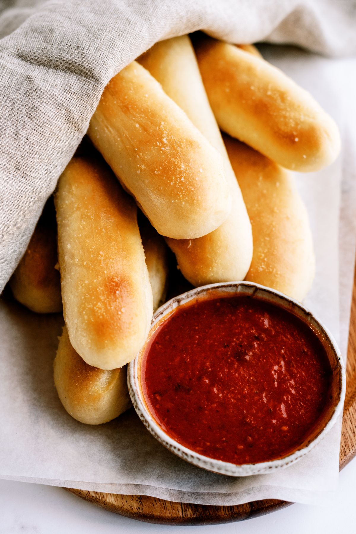 Olive Garden Breadsticks Copycat on a cutting board with a side of marinara sauce