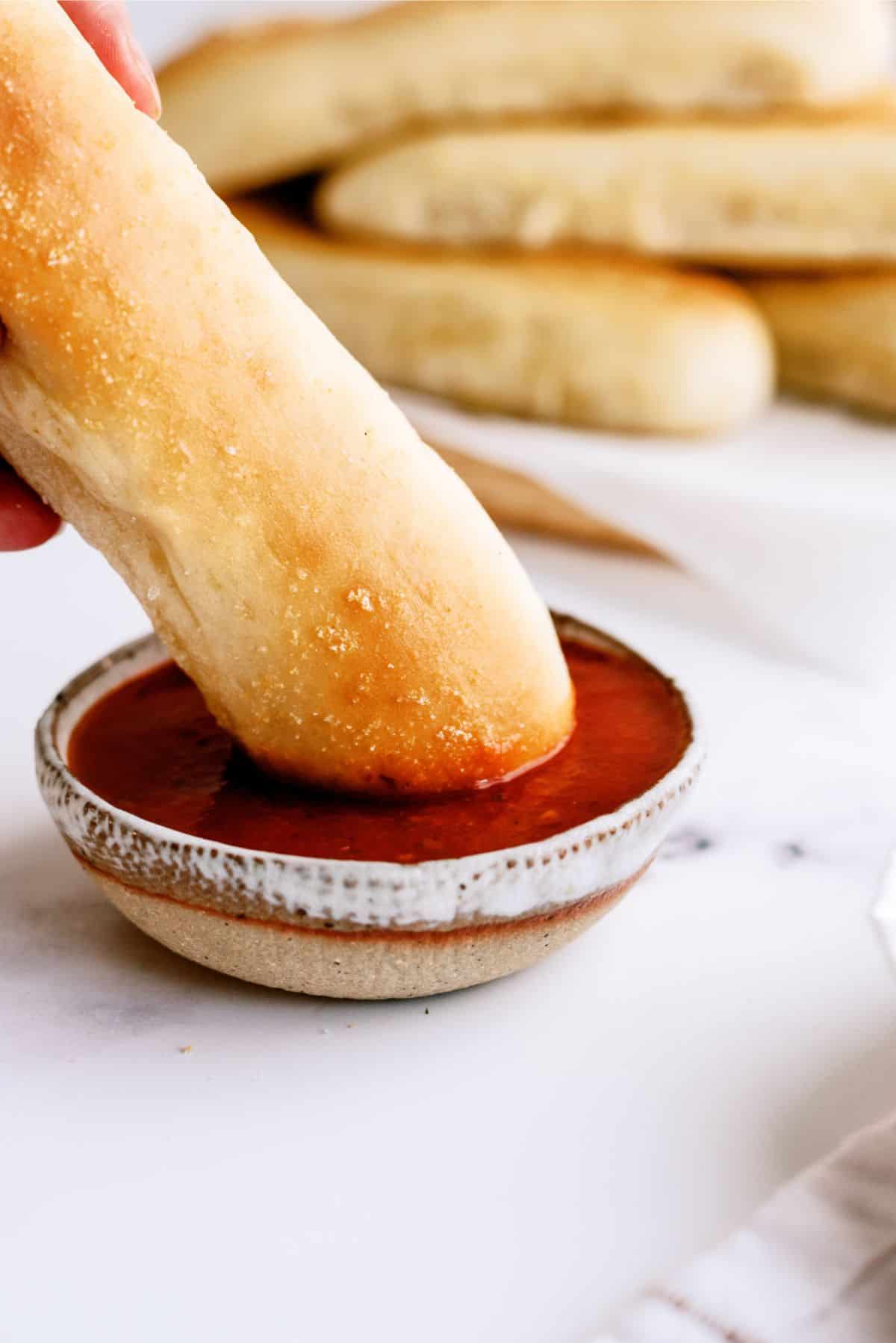 Dipping a Olive Garden Breadsticks Copycat in marinara sauce