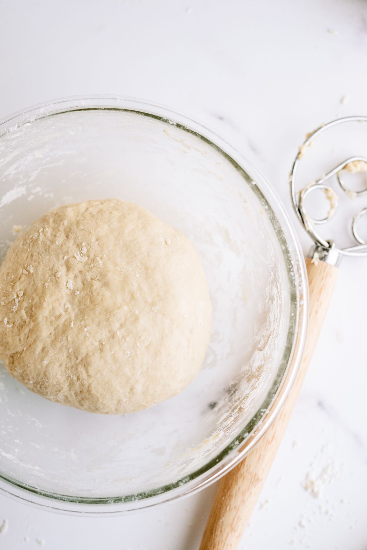 Bread dough rising in a glass mixing bowl