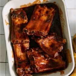 Oven Baked BBQ Ribs in a baking dish covered in BBQ sauce.