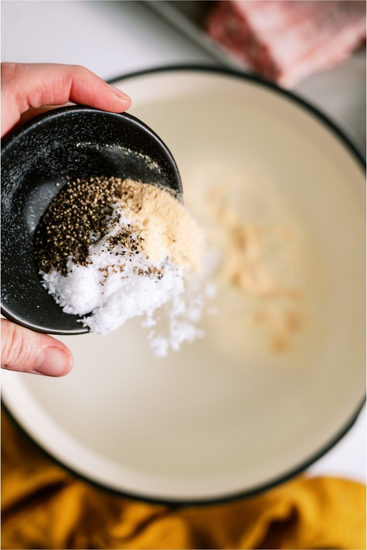 Pouring seasoning into a pot of boiling water.