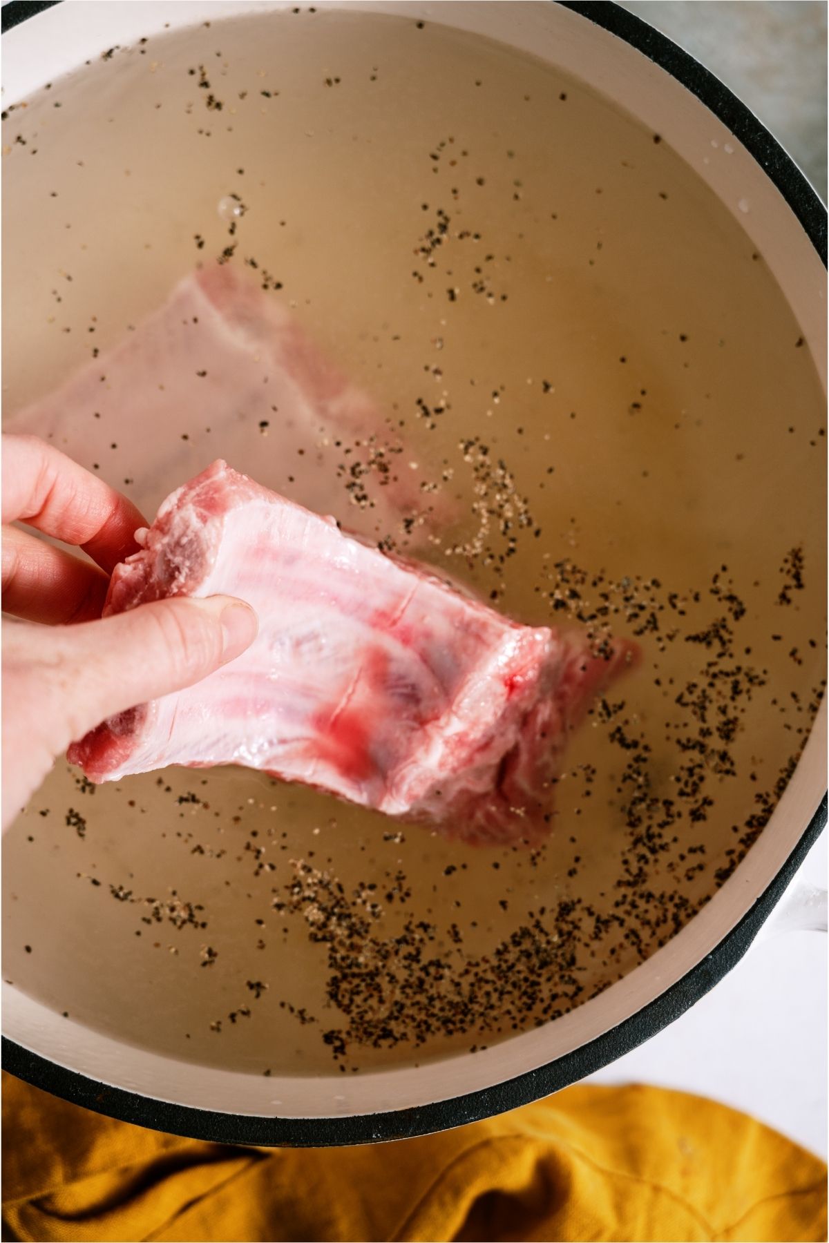 Adding uncooked rib pieces to boiling pot of water.