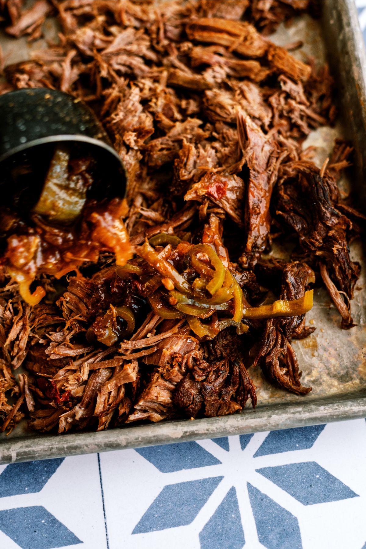 Shredded beef on sheet pan with liquid from the slow cooker poured on top
