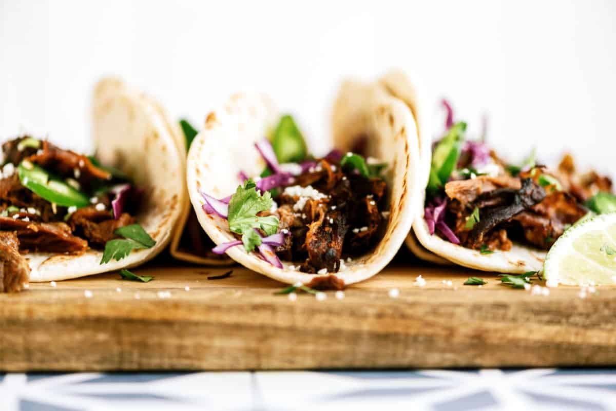 Side view of 3 Slow Cooker Beef Carnitas on a cutting board