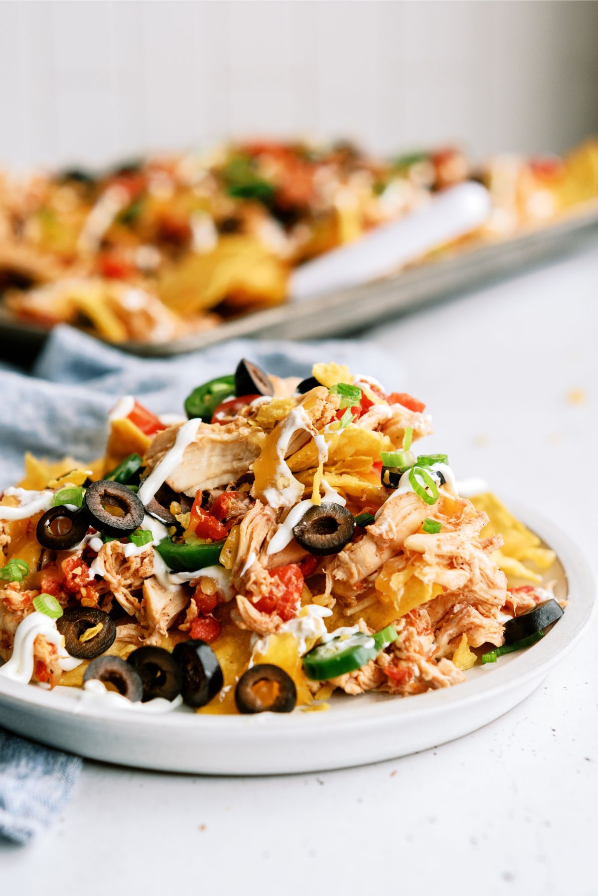 A serving of Slow Cooker Shredded Chicken Nachos on a plate with toppings