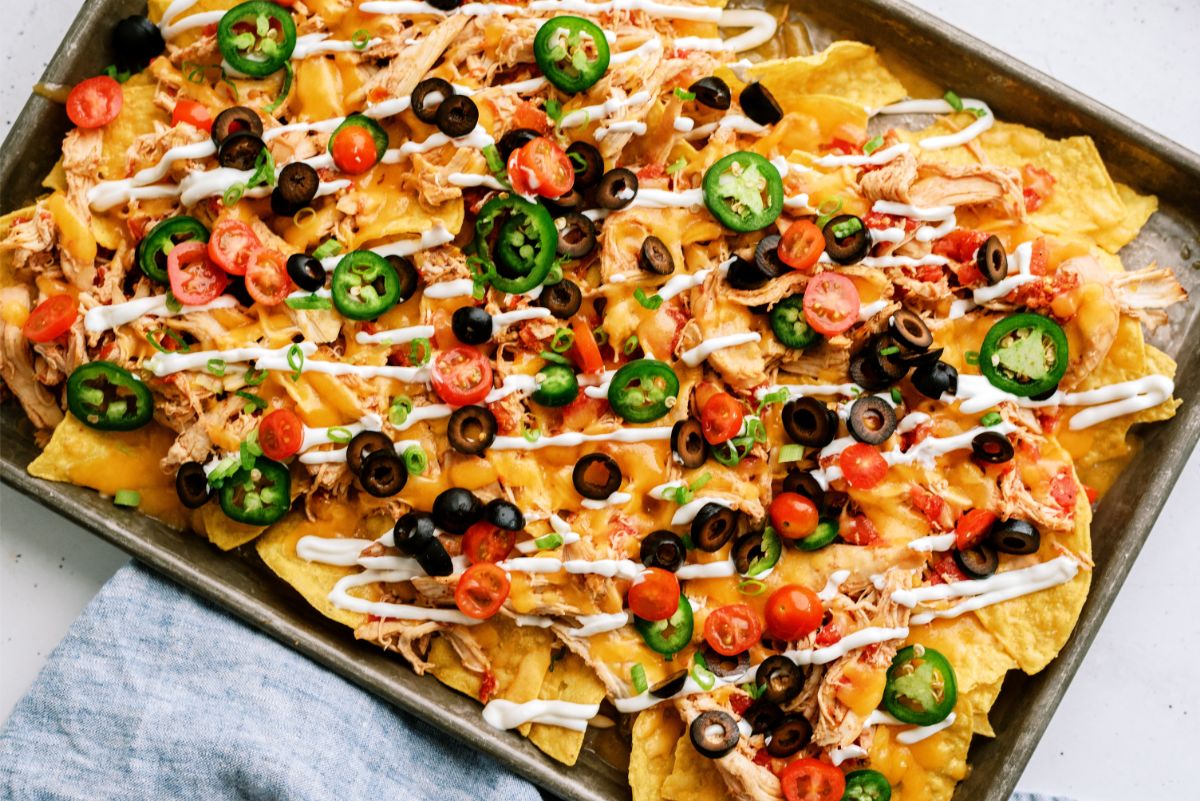 Slow Cooker Shredded Chicken Nachos on a sheet pan topped with toppings