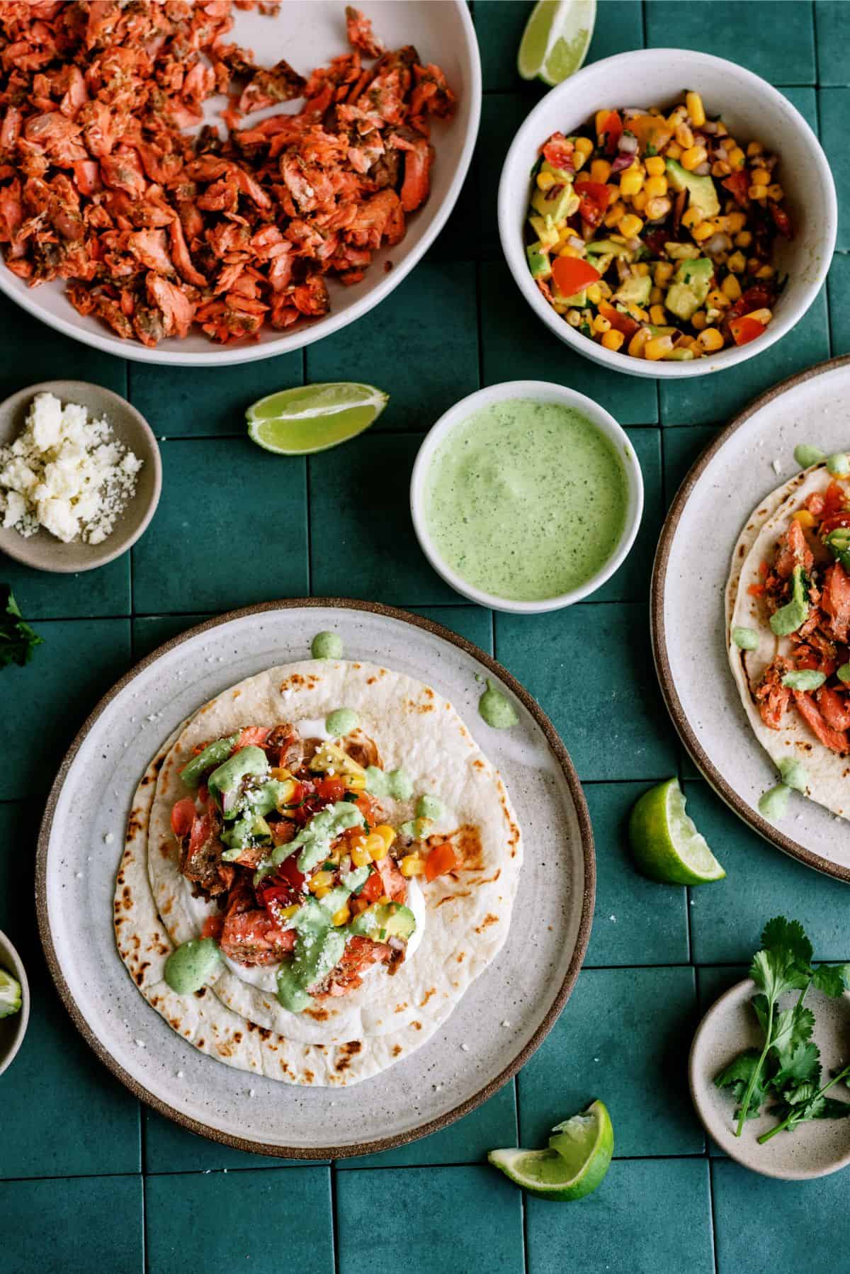 1 Blackened Salmon Taco on a plate surrounded by ingredients to make Blackened Salmon Tacos