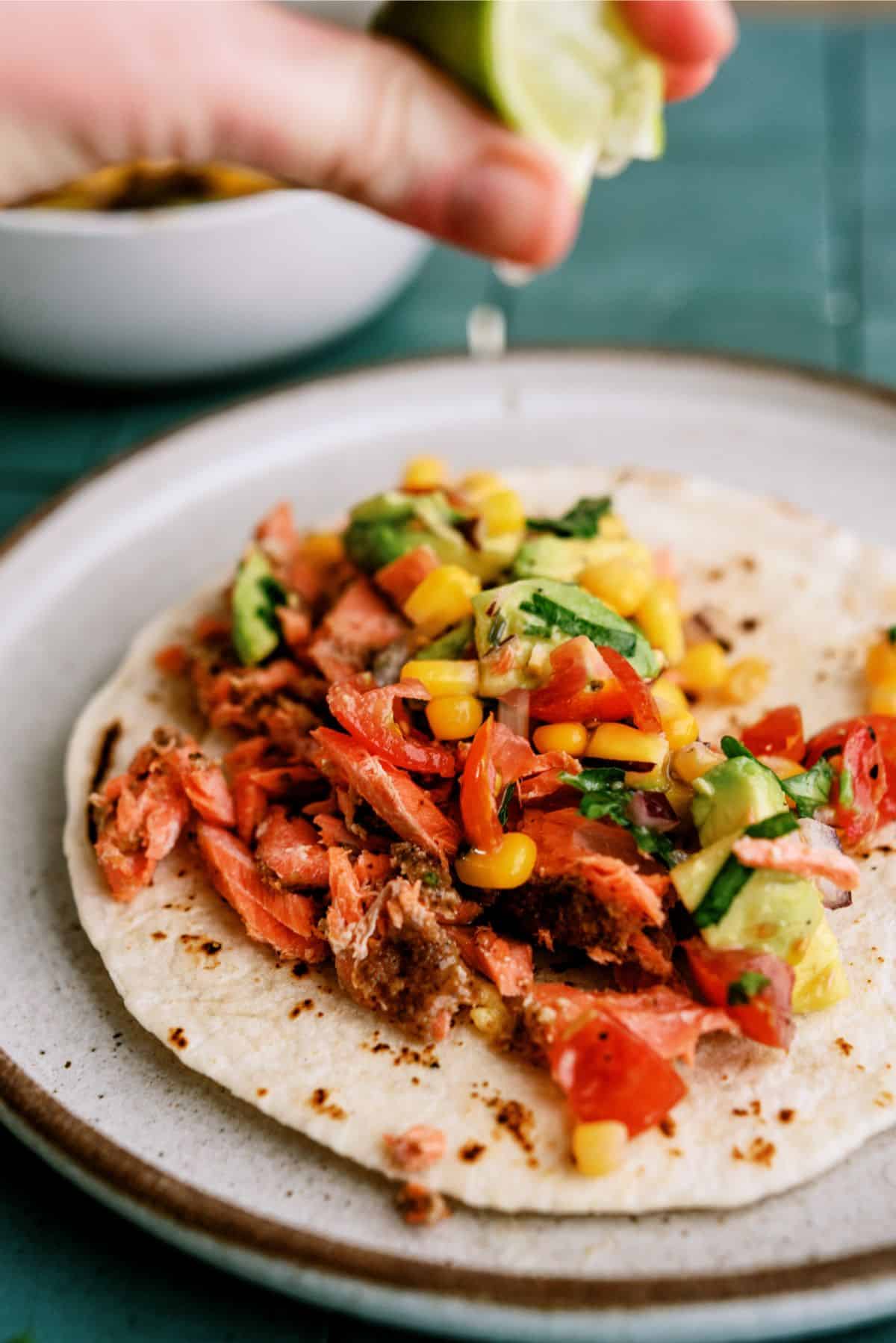 Blackened Salmon Taco on a plate with a fresh lime wedge squeezed on top