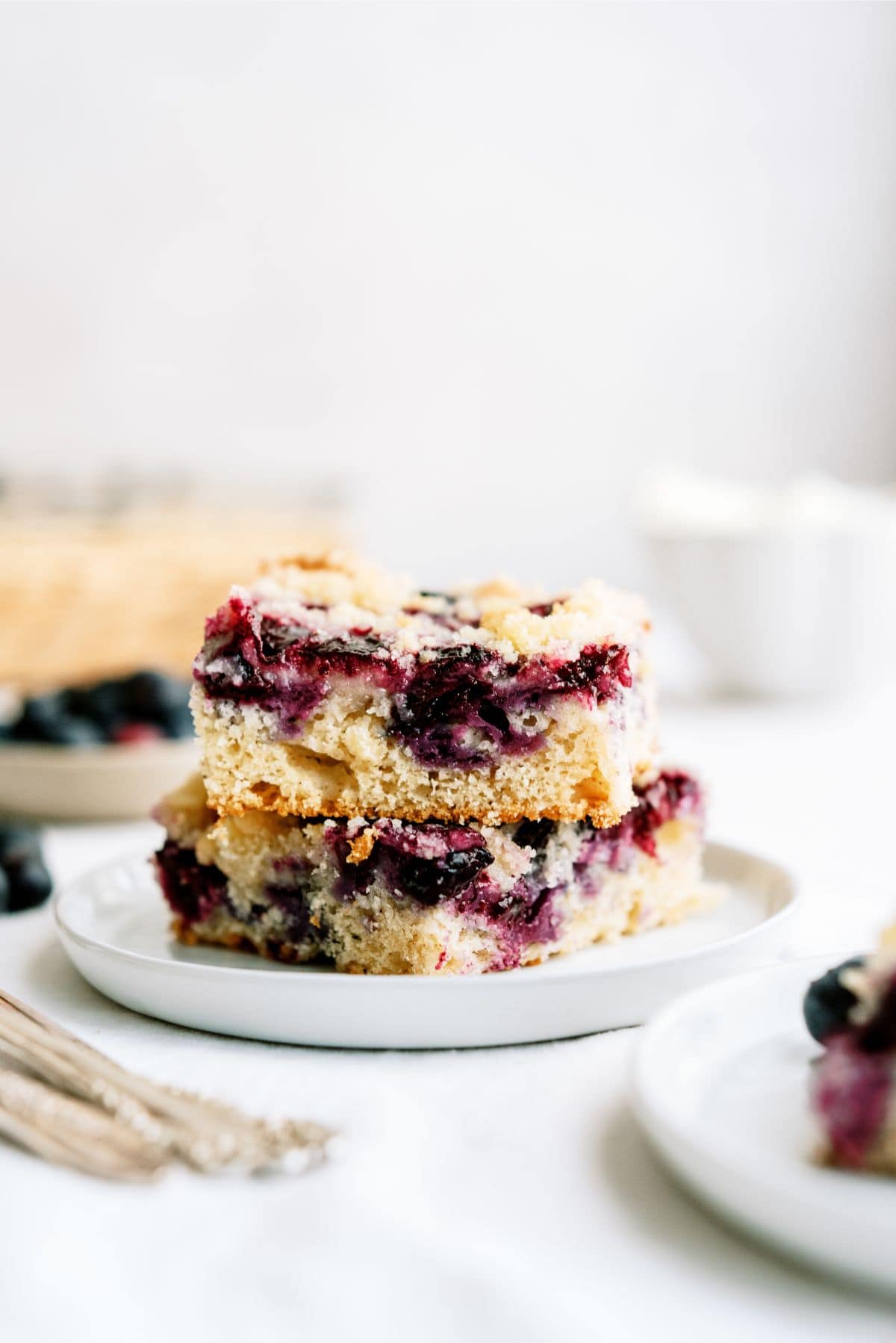 2 squares of Blueberry Coffee Cake stacked on a plate