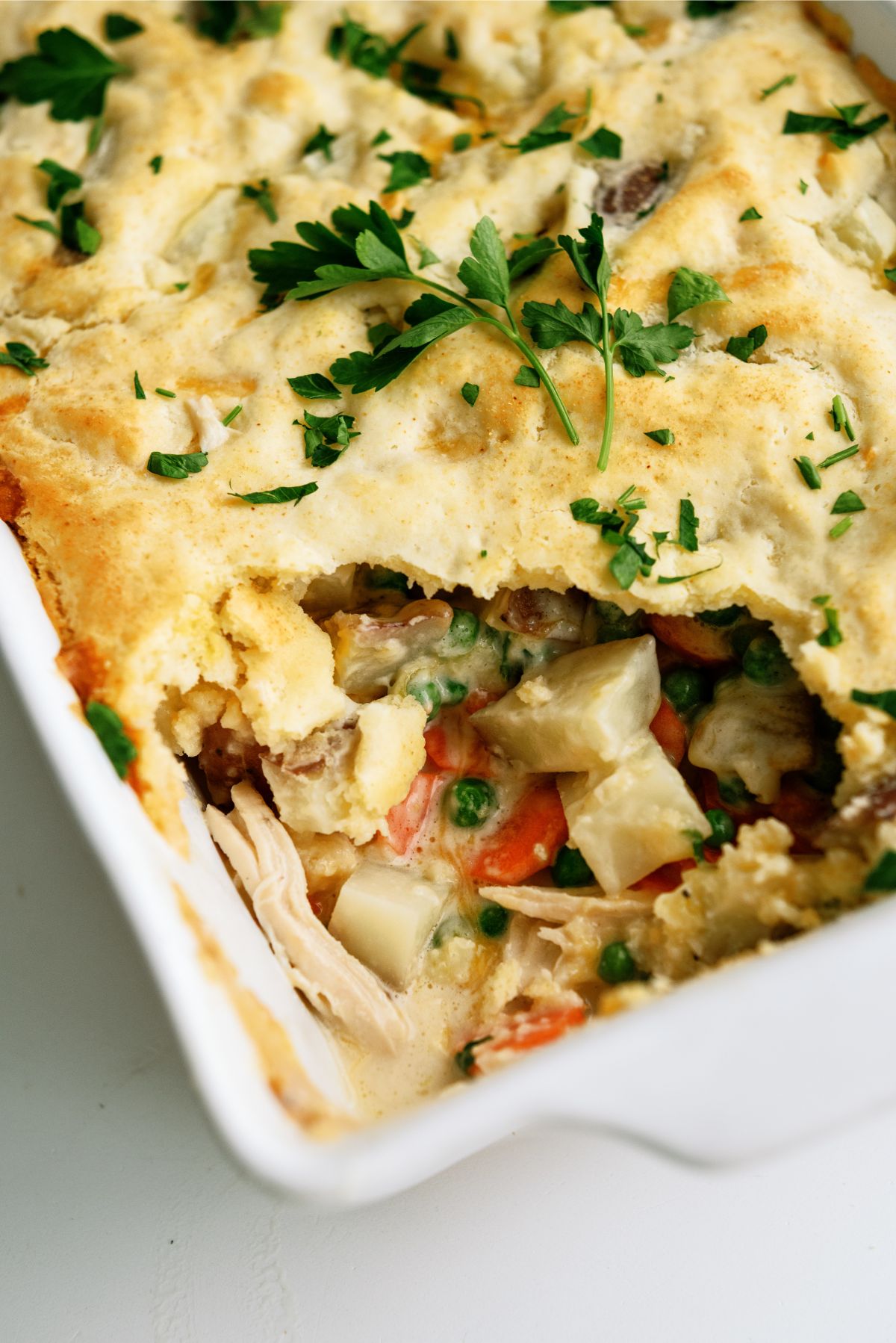 Baked Cheesy Chicken Pot Pie in casserole dish with the corner serving missing
