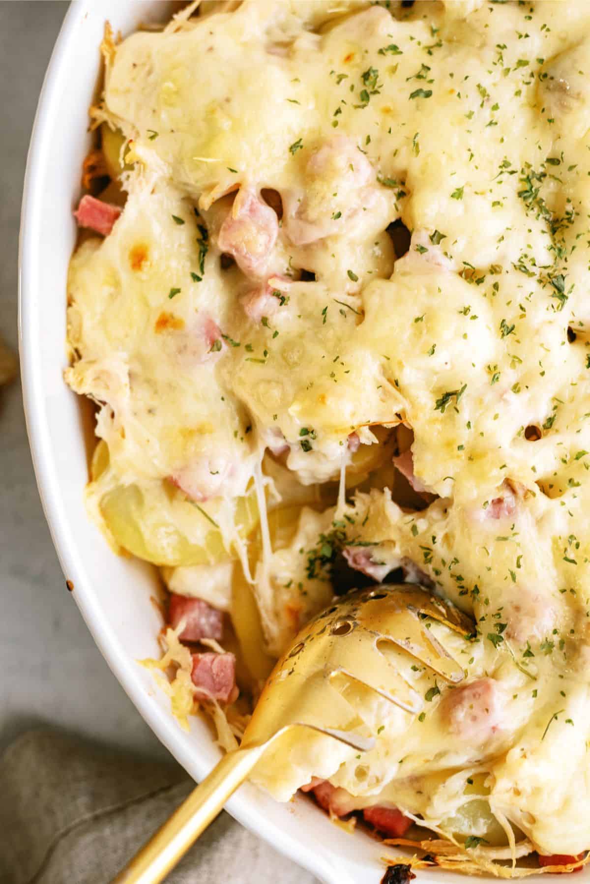 Top view of Chicken Cordon Bleu and Potatoes Casserole in a casserole dish with a serving spoon.