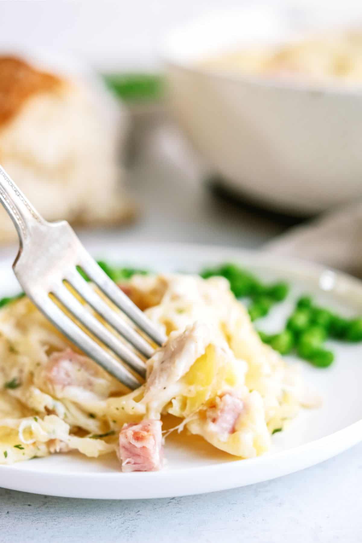 A serving of Chicken Cordon Bleu and Potatoes Casserole on a plate with a fork