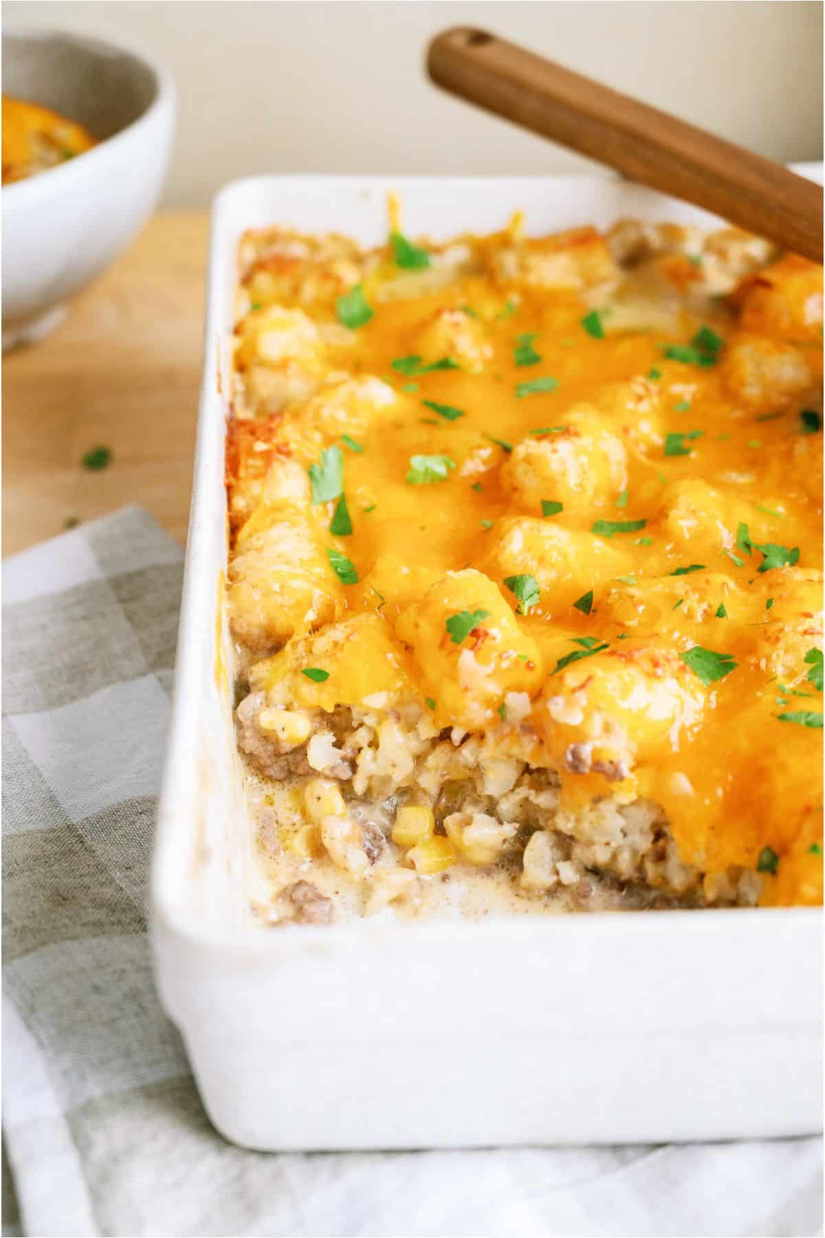 A scoop of Cowboy Casserole (Tater Tot Casserole) missing from the casserole dish to show the inside.