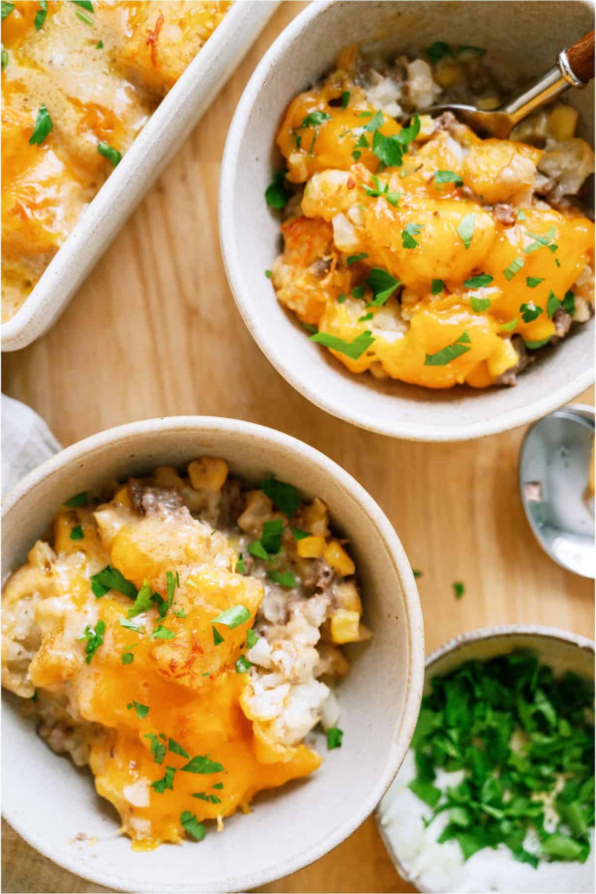 Top view of two bowls of Cowboy Casserole (Tater Tot Casserole) with the remaining casserole in the background.