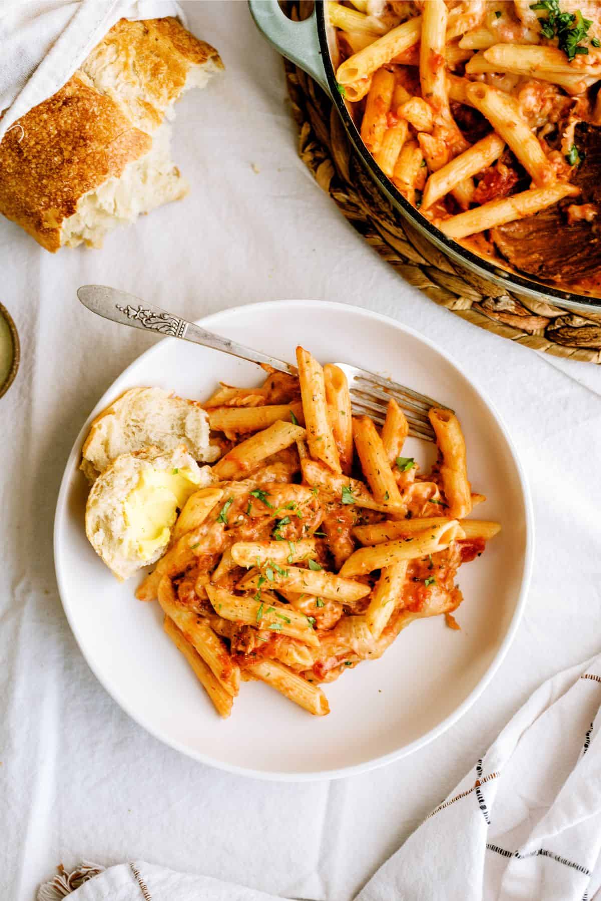 A serving of Pink Sauce Chicken Pasta Bake on a plate with a side of bread