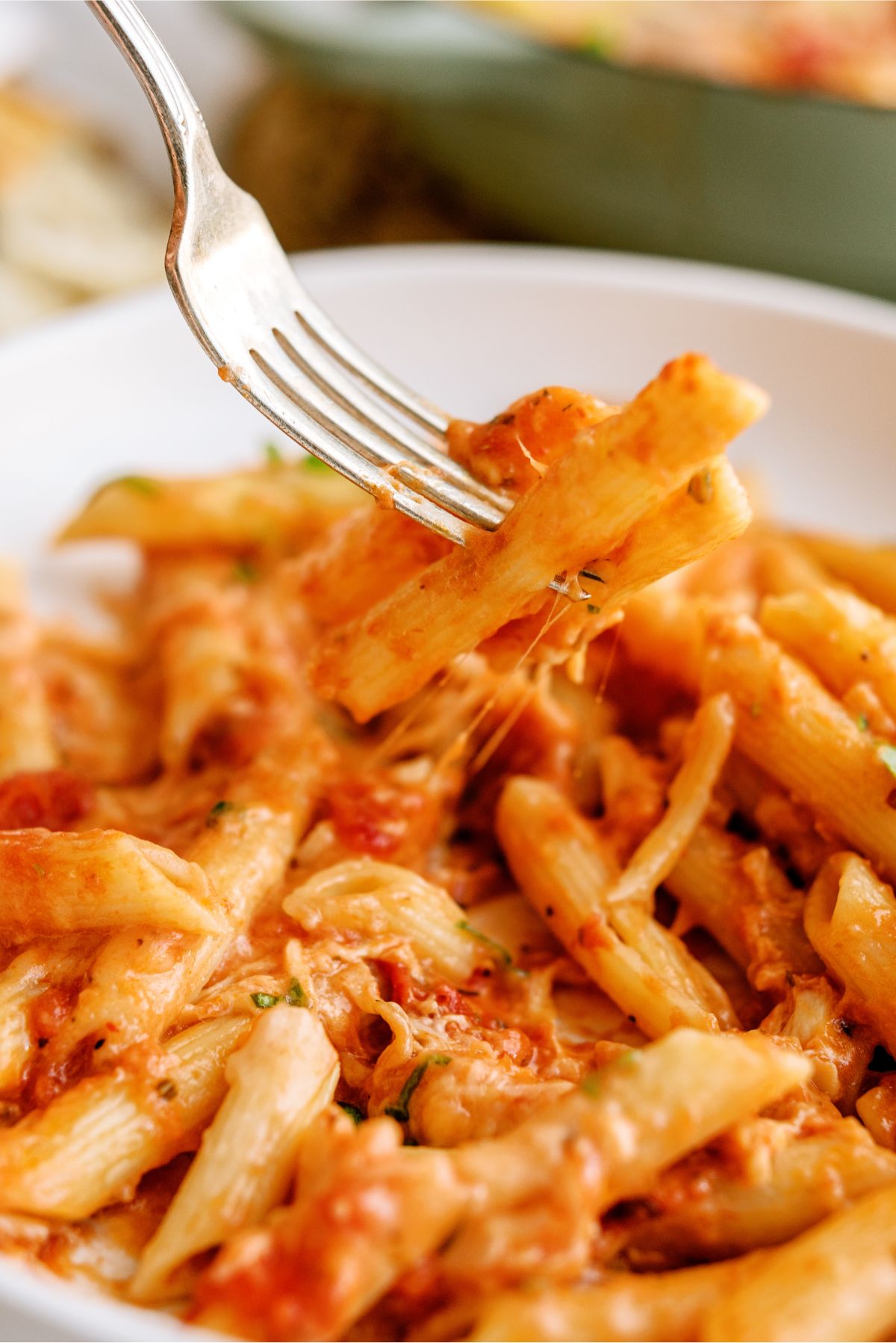 Close up of a serving of Pink Sauce Chicken Pasta Bake on a plate with a fork