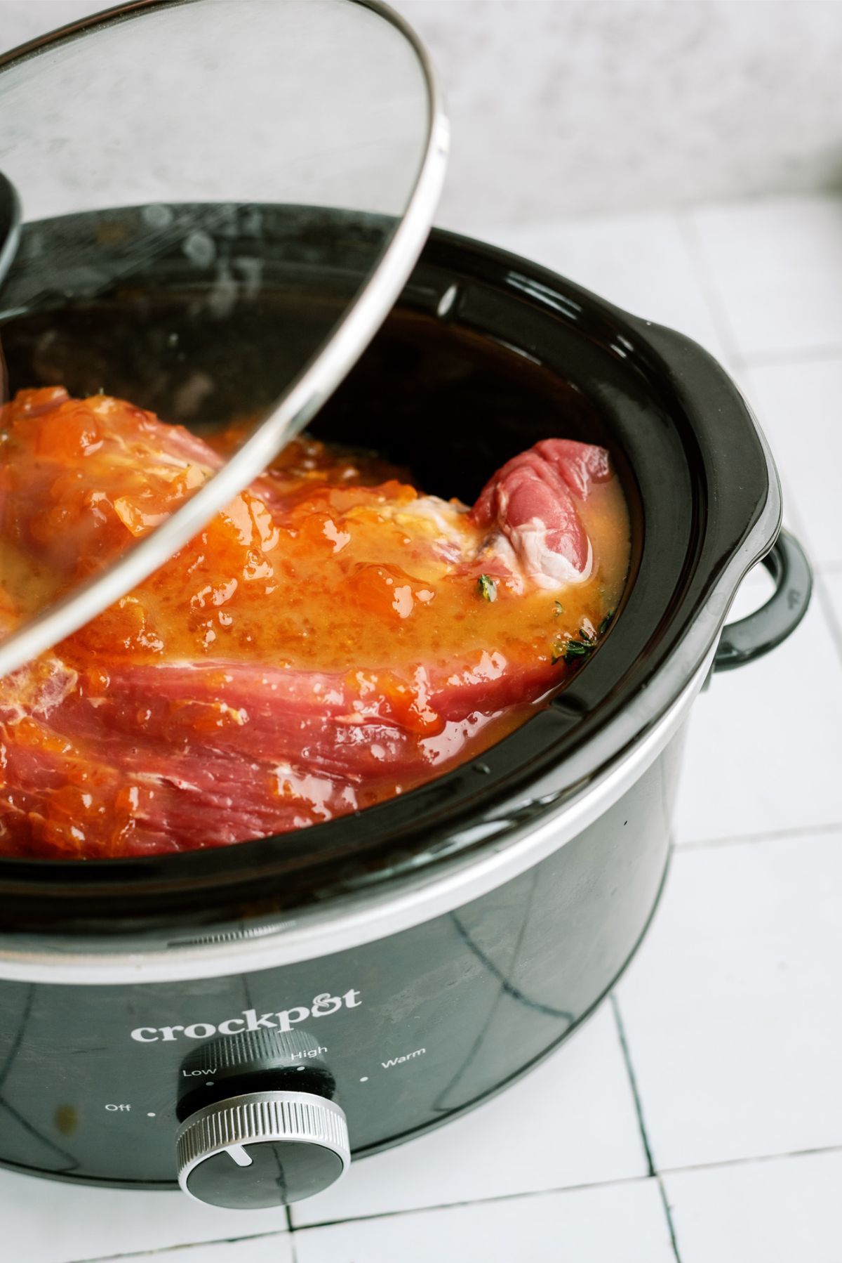 Putting the lid on the slow cooker with the pork and veggies inside.