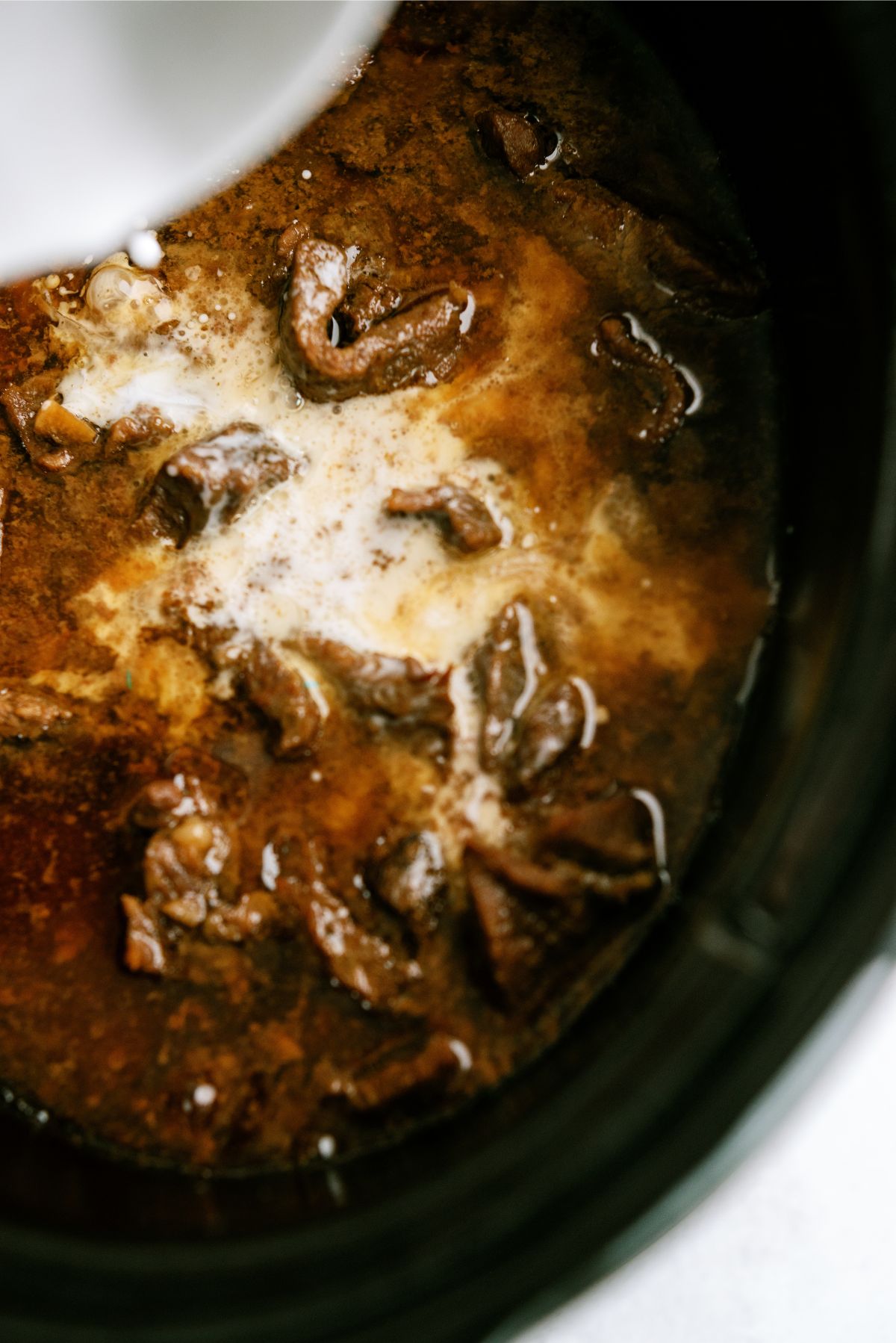 Pouring Cornstarch mixture over beef and slow cooker