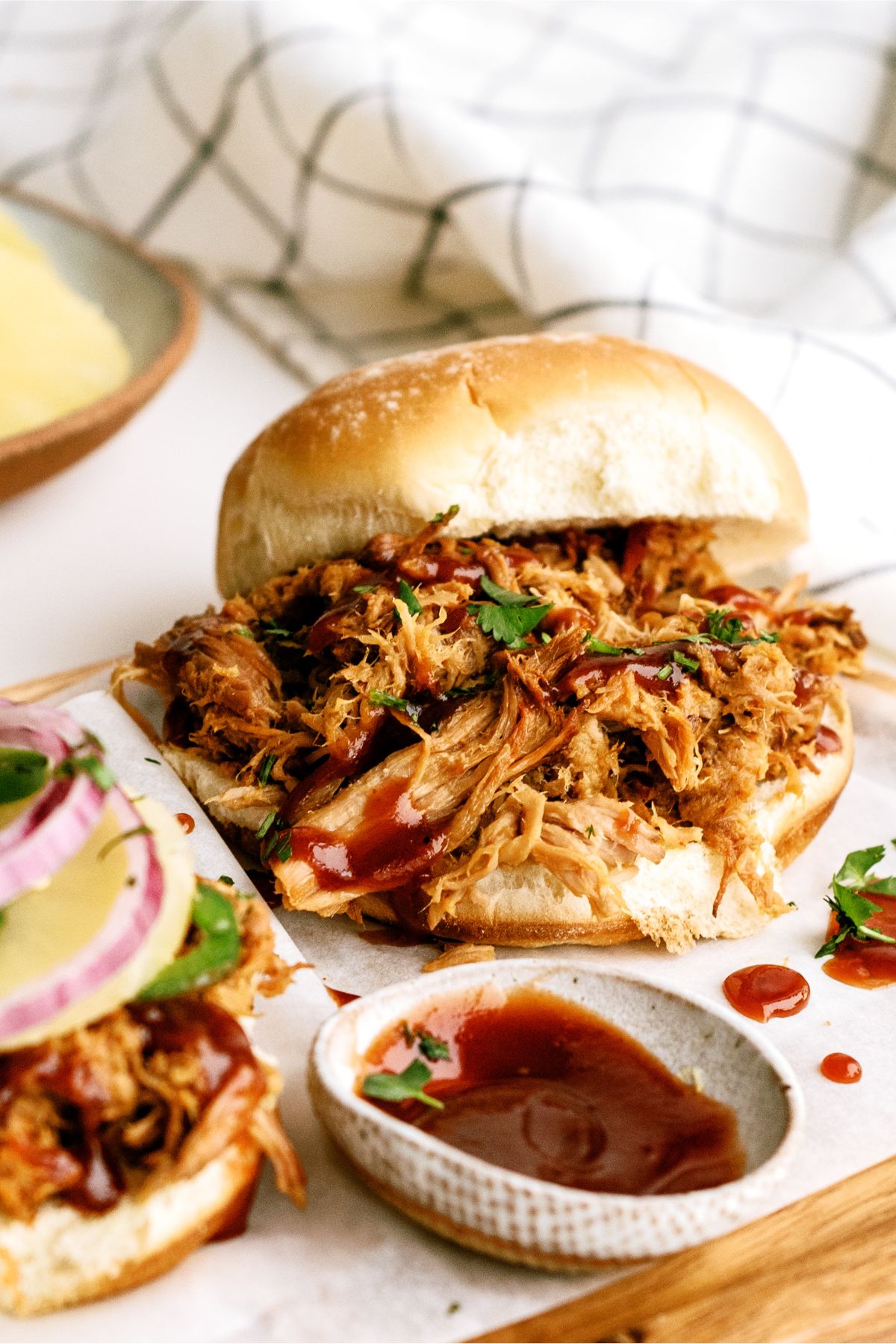 Closer up of Slow Cooker Pineapple Pulled Pork Sandwich with a side of BBQ sauce