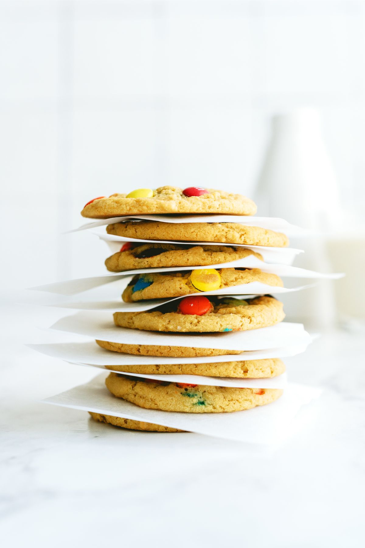 Chewy M&M Cookies stacked with parchment paper in between them.