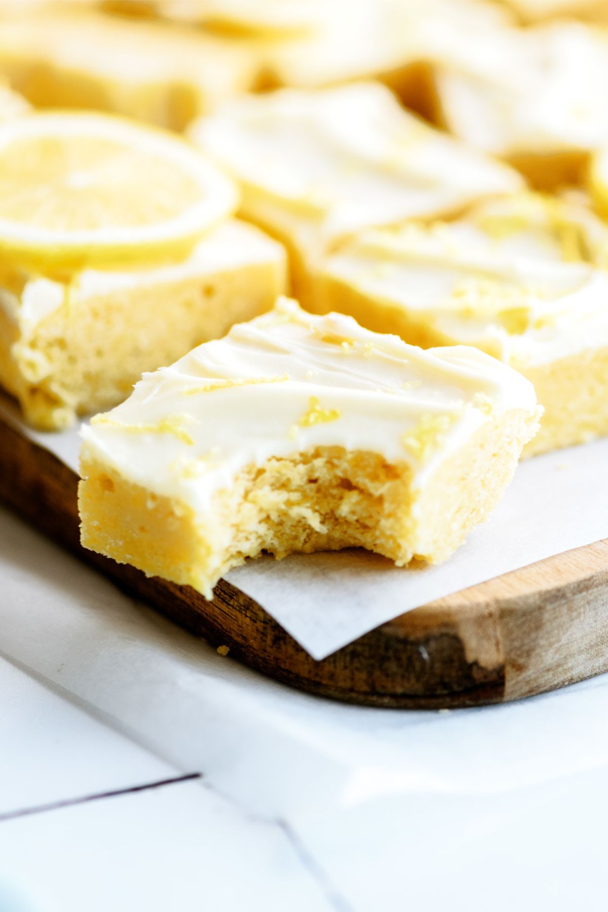 Lemon Brownies with Lemon Frosting cut into squares with a bite missing out of one.