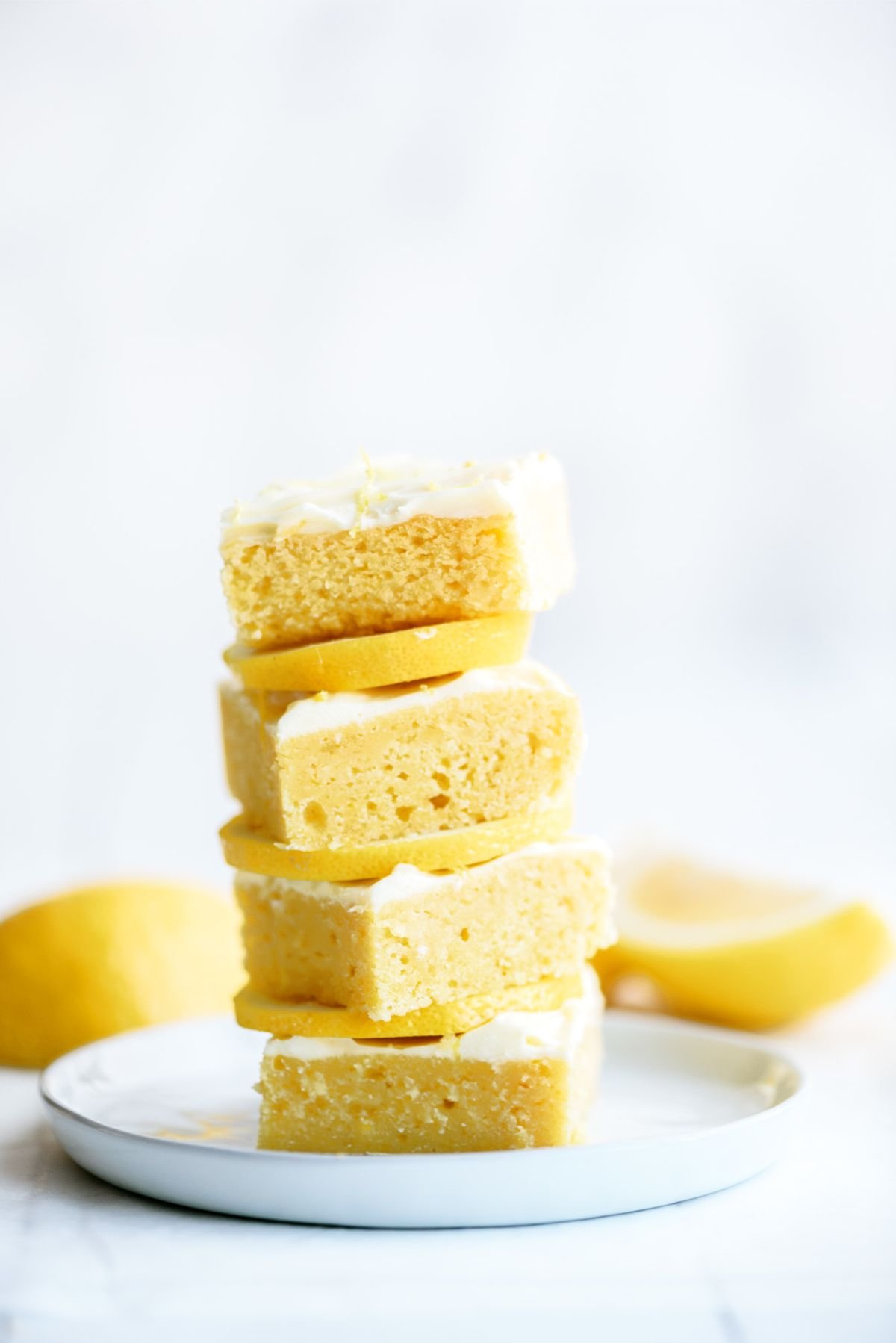 Lemon Brownies with Lemon Frosting cut into squares and stack on a plate.