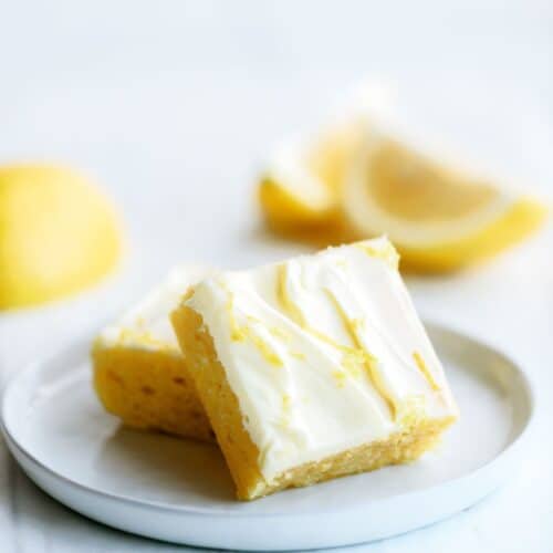Lemon Brownies with Lemon Frosting on a plate with lemon slices.