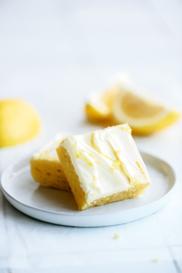 Lemon Brownies with Lemon Frosting on a plate with lemon slices.