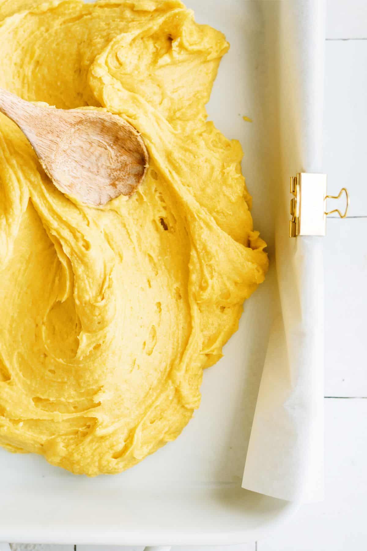 Spreading brownie batter onto prepared pan with wooden spoon.
