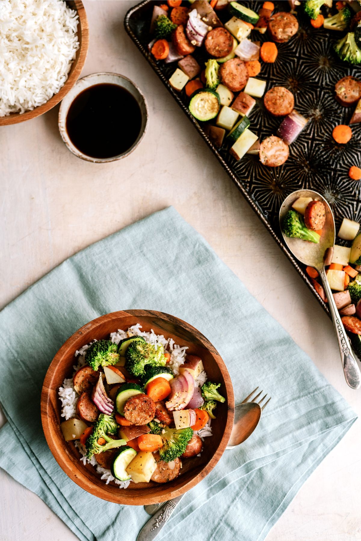 One Pan Garlic Sausage and Vegetables on a sheet pan with one serving in a bowl