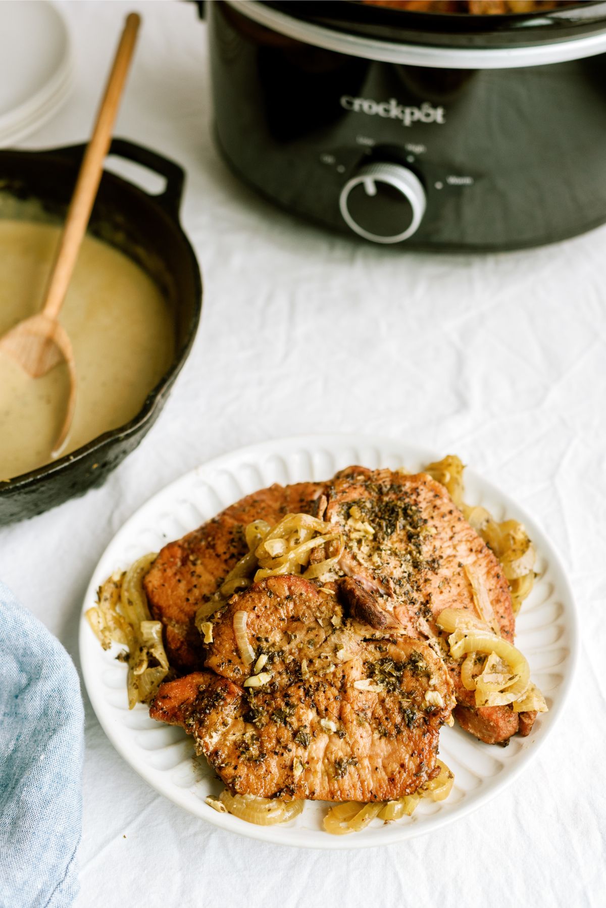 A slow cooker, pan of gravy and plate of cooked pork chops