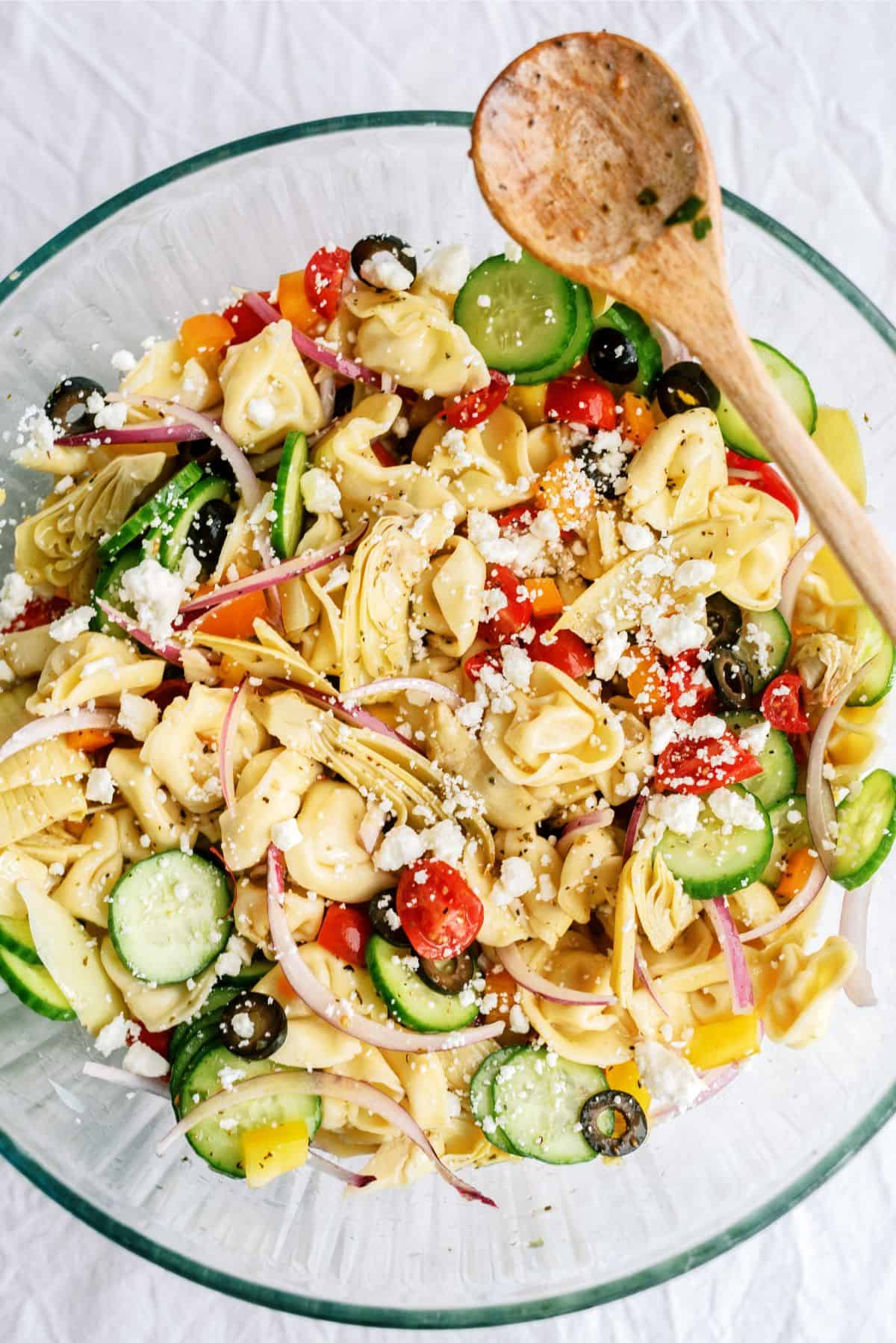 Tortellini Pasta Salad in a mixing bowl with a wooden spoon