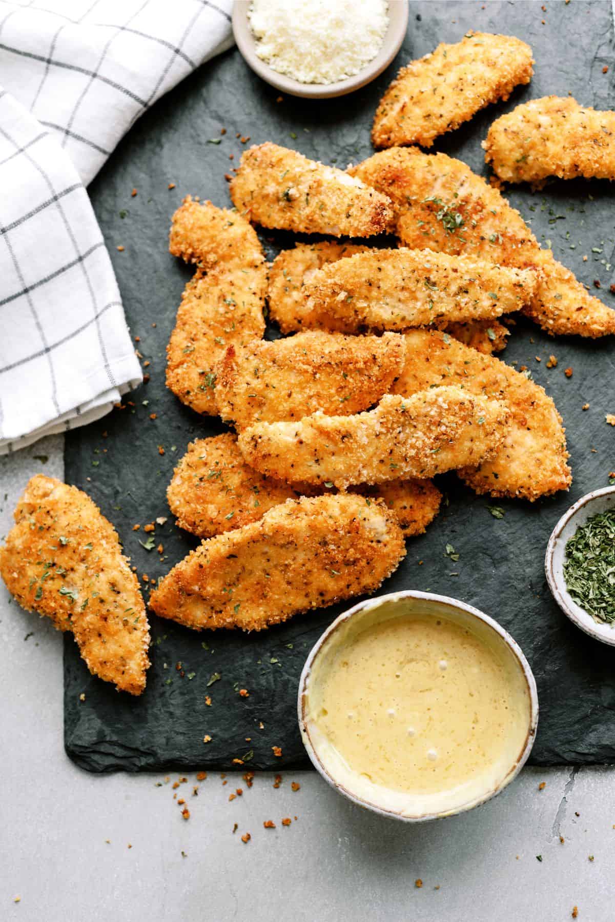 Baked Panko Chicken on a cutting board with a side of dipping sauce